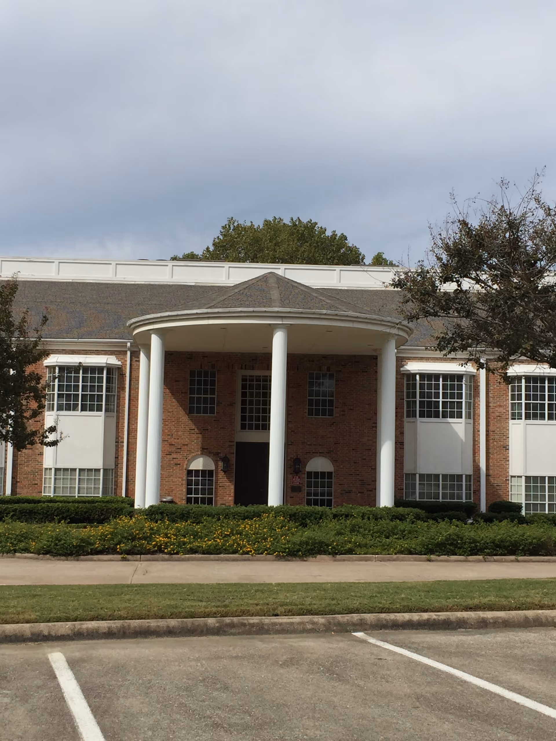 Brick senior living facility front entrance with circular portico and white columns.