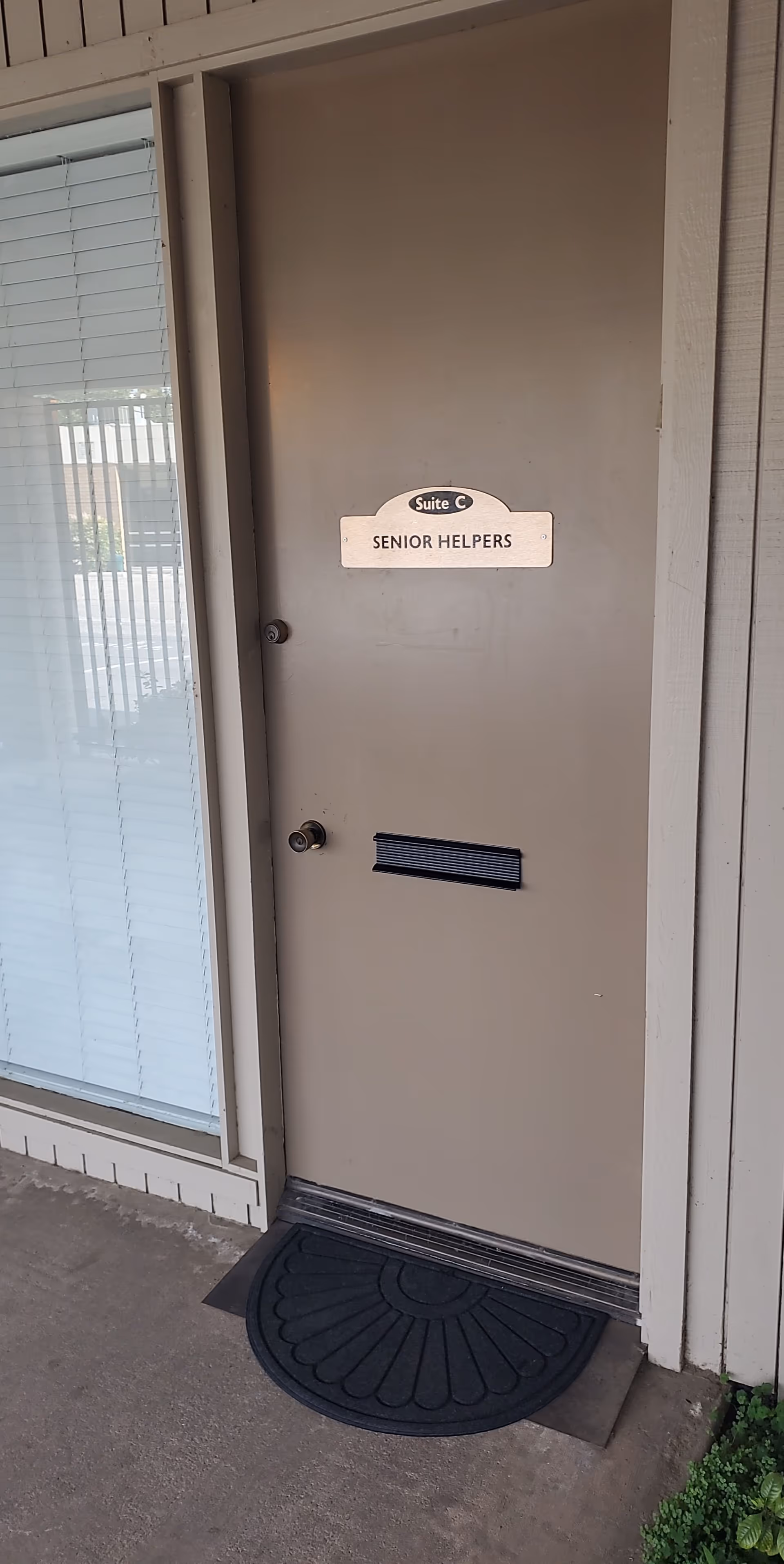 Exterior door labeled Suite C Senior Helpers beside a window with blinds.