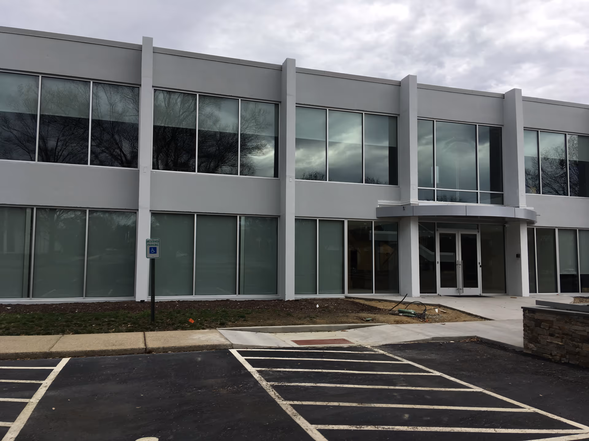 Modern gray two-story facility facade with large glass windows and a front entrance
