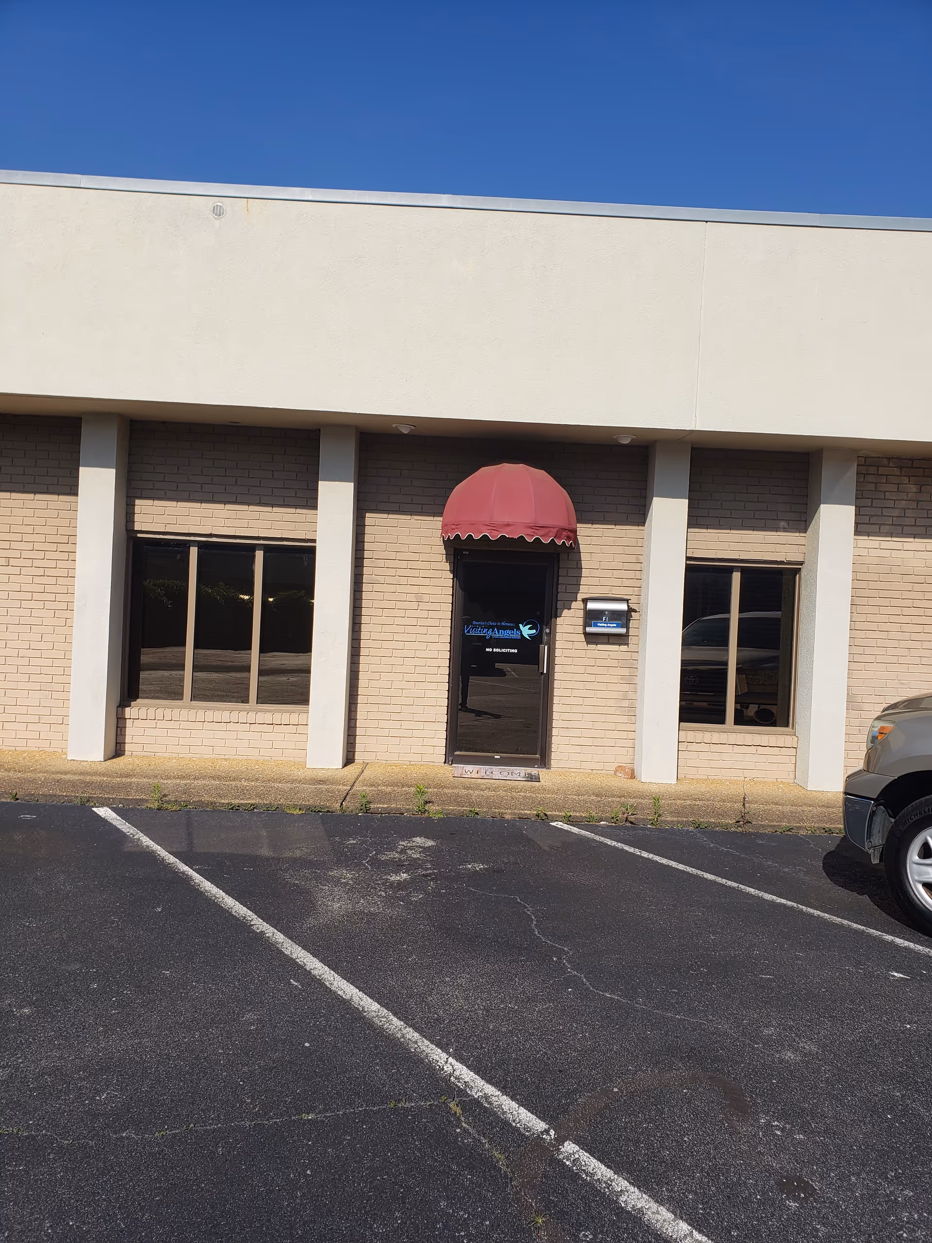 Exterior view of Visiting Angels Senior Home Care building with a red awning over the entrance.