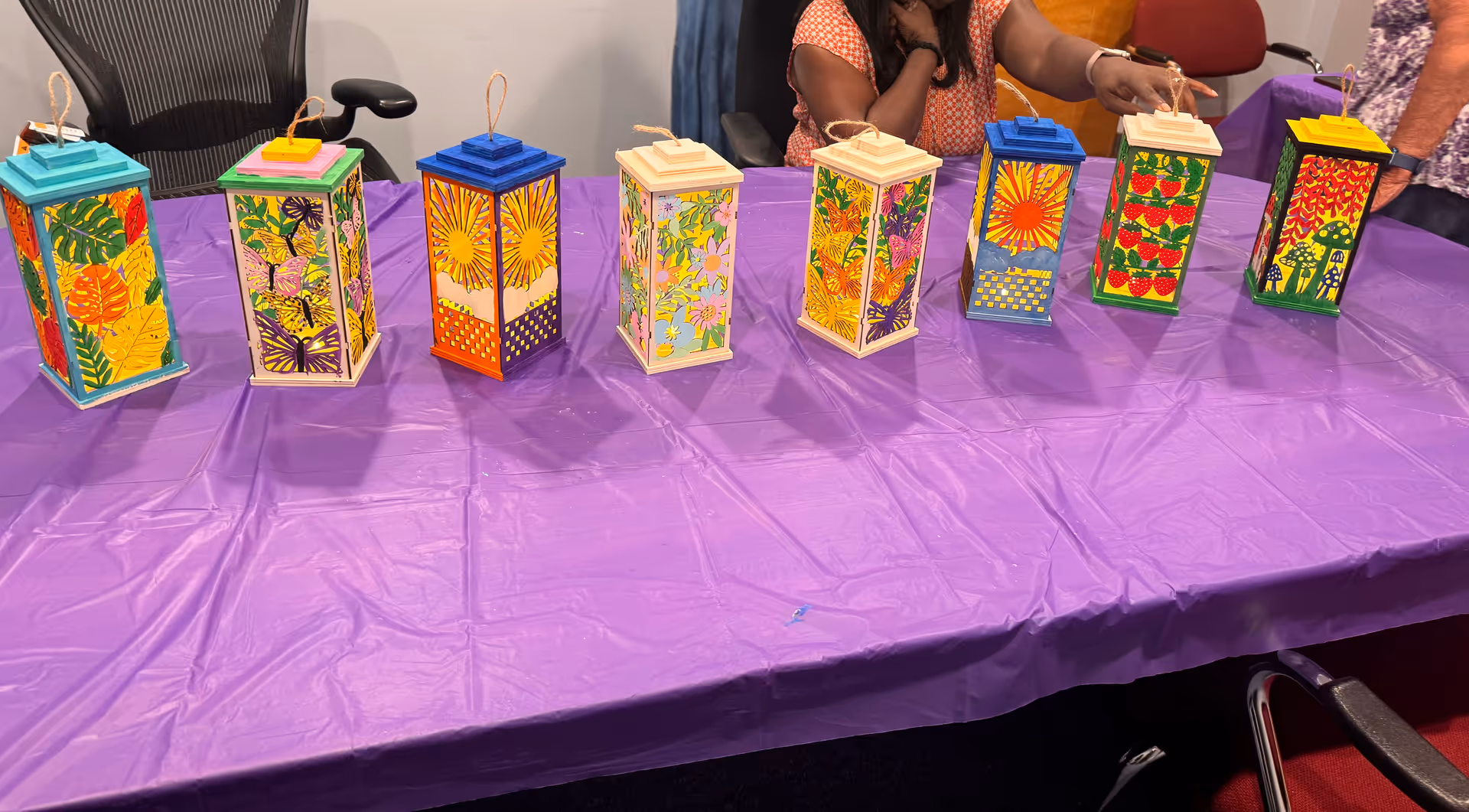 Colorful lanterns lined up on a purple table during a crafts activity.