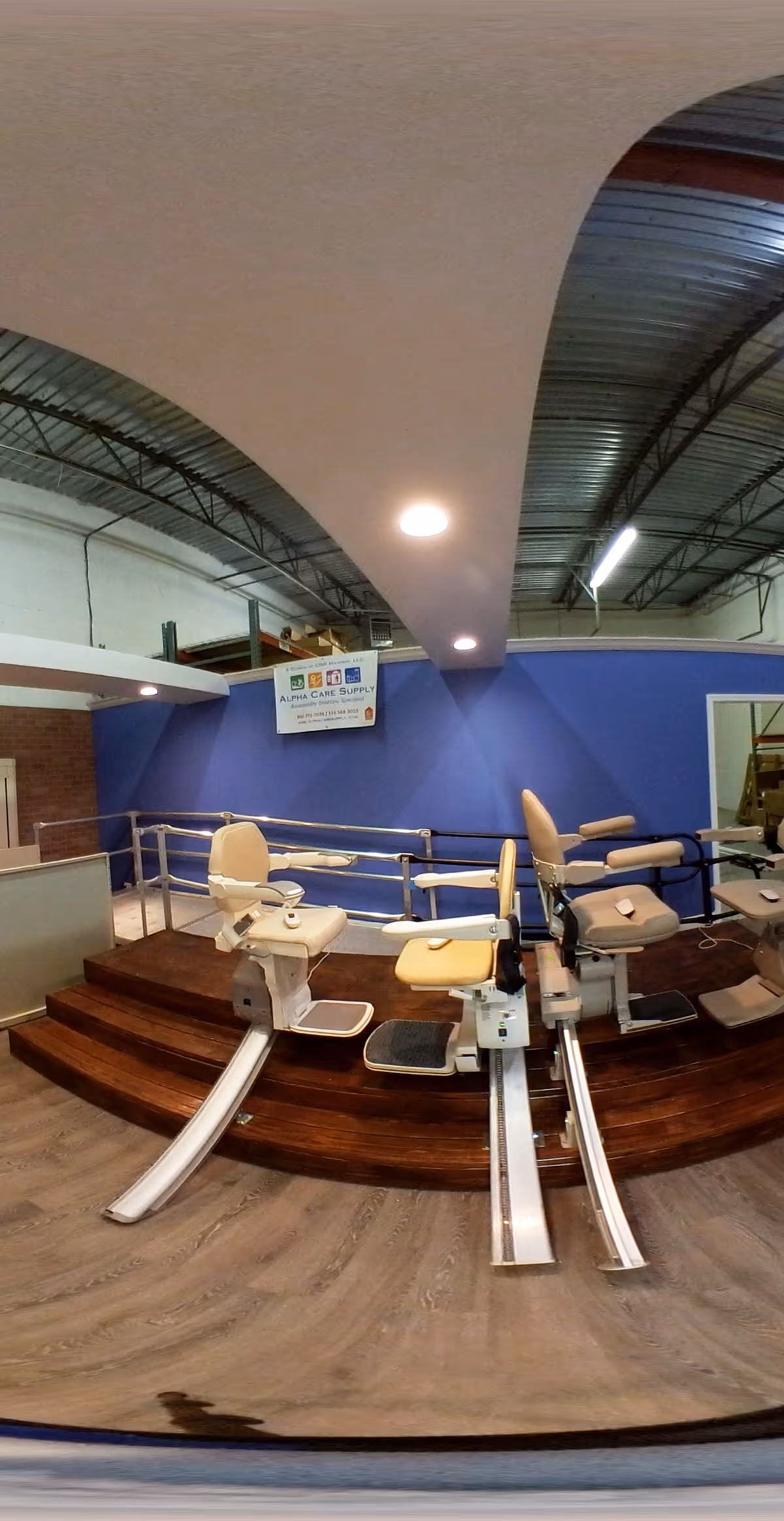 Interior showroom displaying beige medical chairs on a curved wooden platform against blue walls.