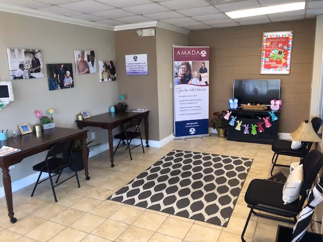 Interior reception area of Amada Senior Care with desks, chairs, photos, banner, and a patterned rug.