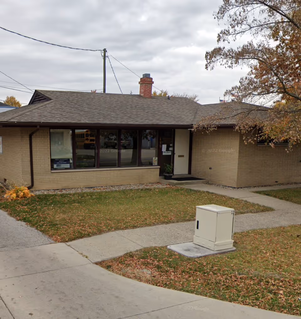 Single-story brick facility with large front windows, a small entry, and surrounding lawn.