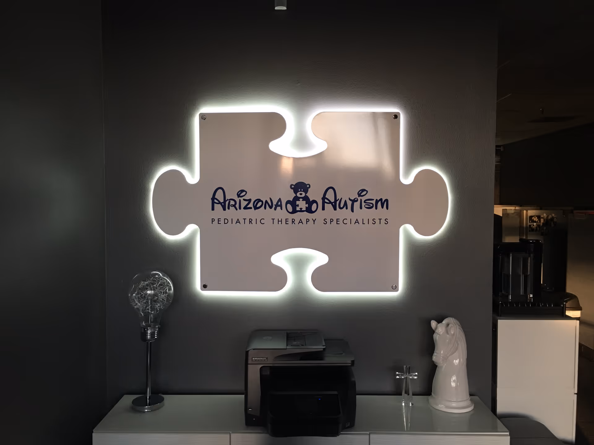 Interior lobby with an illuminated puzzle-piece logo reading Arizona Autism.