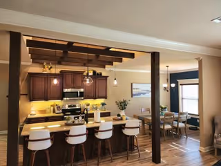 Open-concept kitchen with dark wood cabinets, island seating, and a dining area.