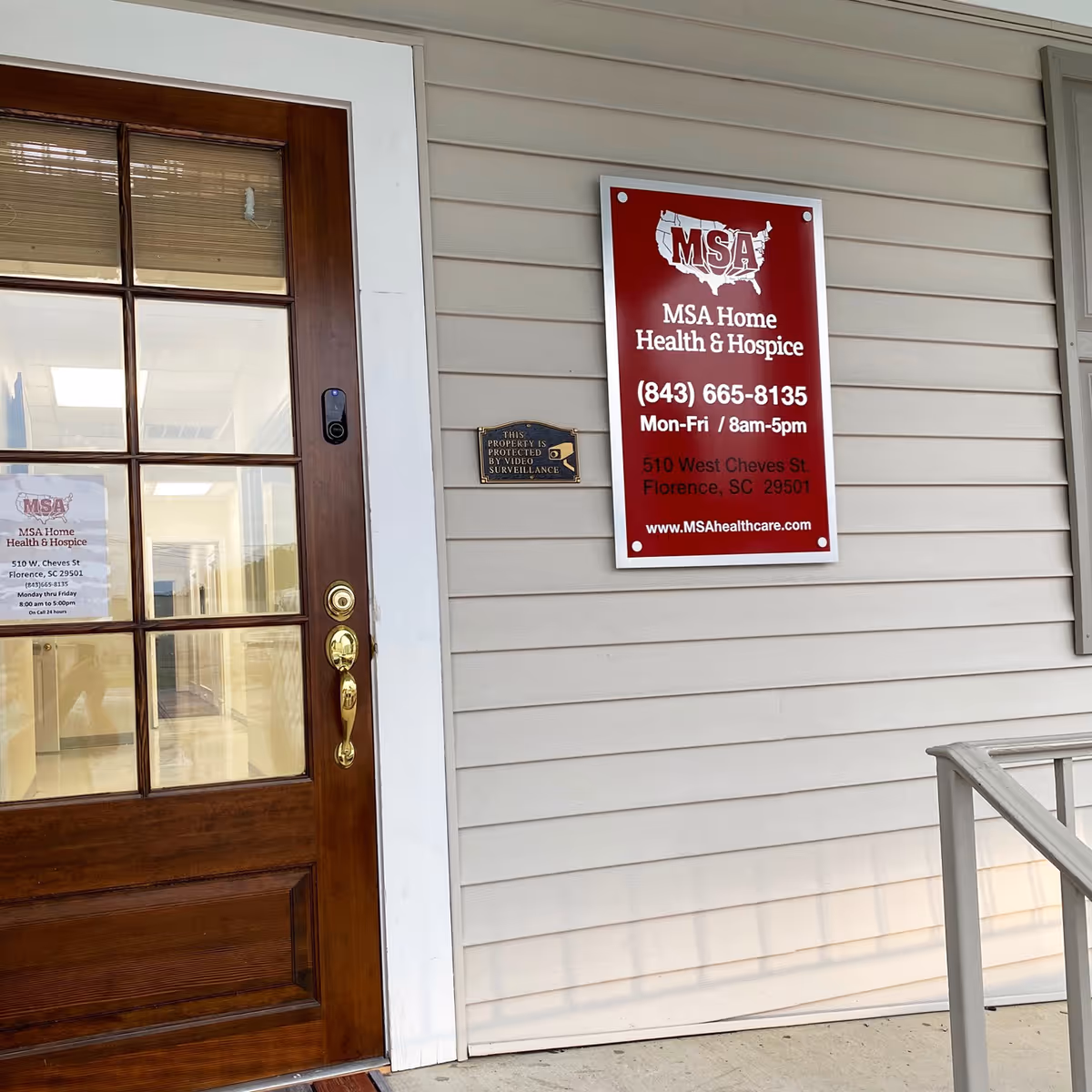 Exterior view of a beige building entrance with a red MSA Home Health & Hospice sign.