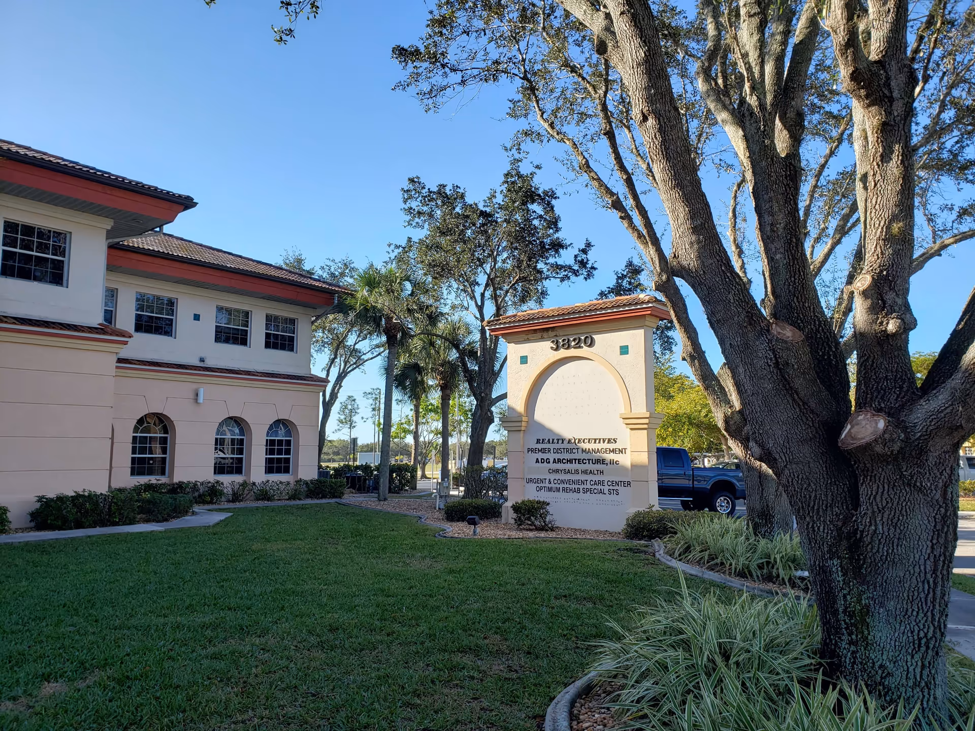 Exterior view of a beige facility building with an arched entrance sign and palm trees.