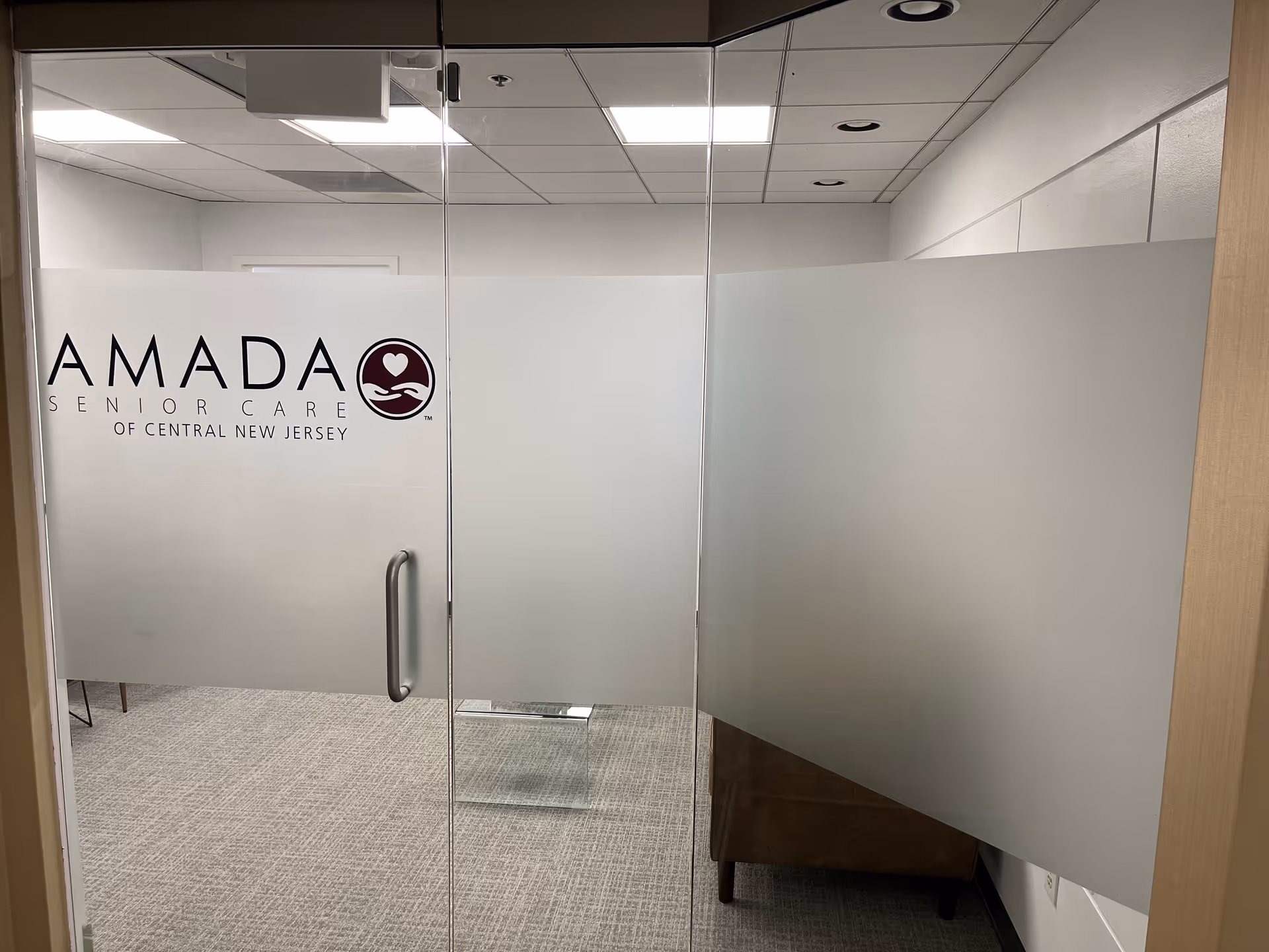 Interior glass entry featuring Amada Senior Care branding on frosted panels.