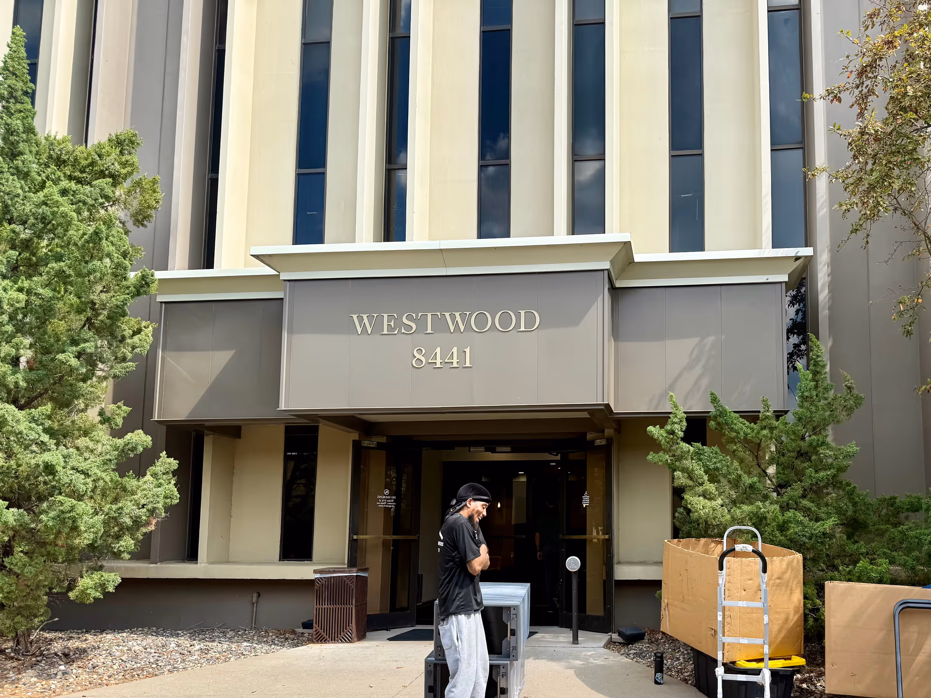Exterior view of a tall building entrance labeled Westwood 8441 with a person nearby.