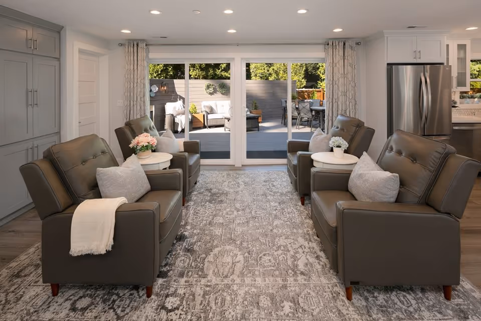 Bright, modern living room with four gray armchairs and sliding glass doors.