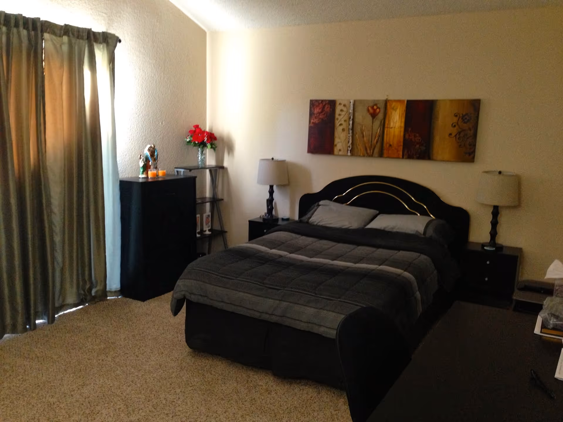 Cozy bedroom with a large bed, nightstands, lamps, dresser, and decorative wall art.