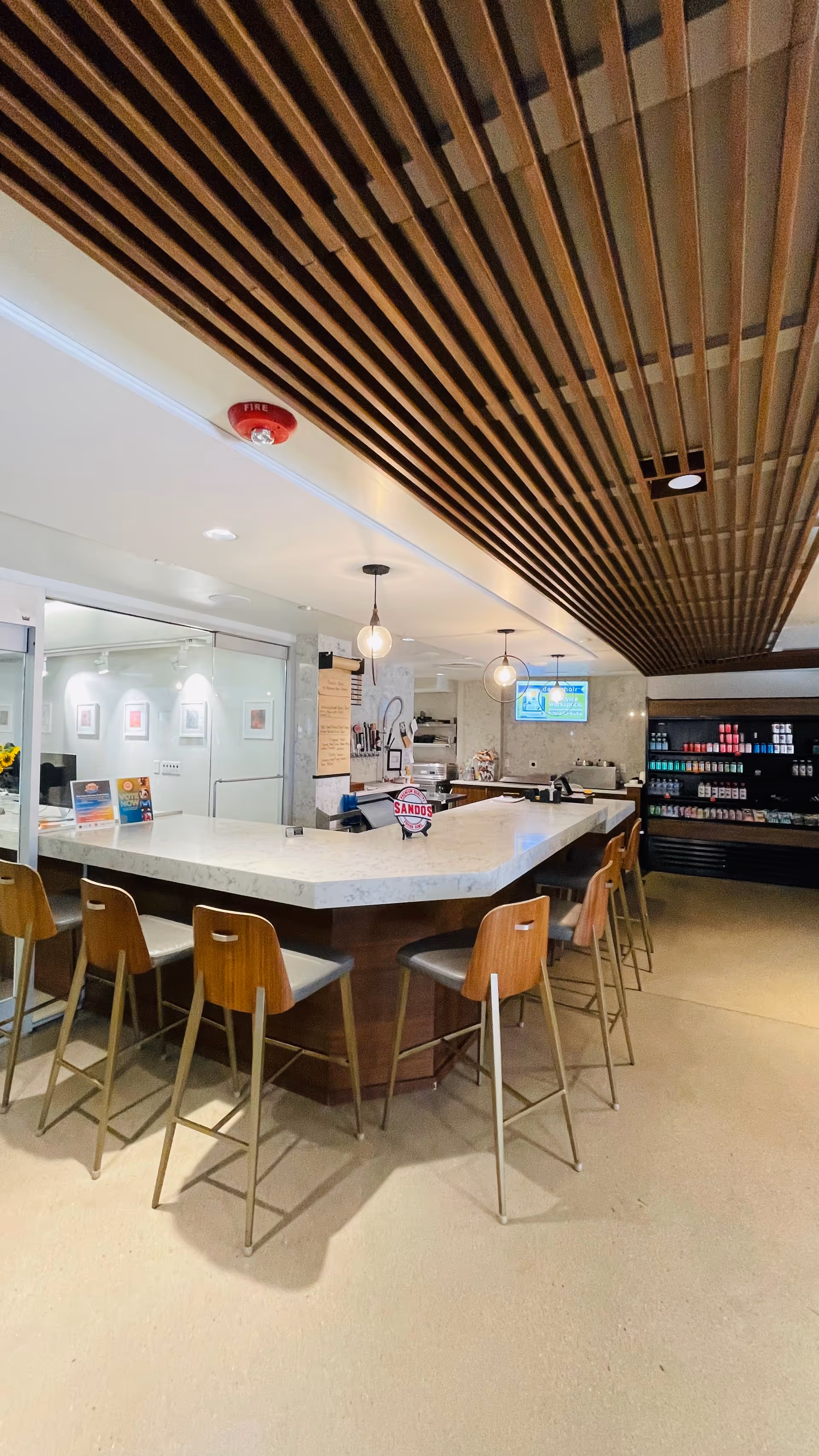 Interior cafe-style dining area with a long marble counter and wooden stools.