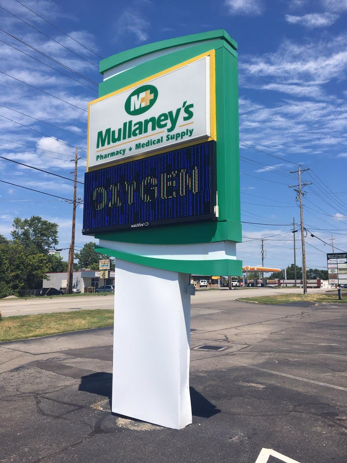 Tall green Mullaney's Pharmacy and Medical Supply sign over a white support pillar.