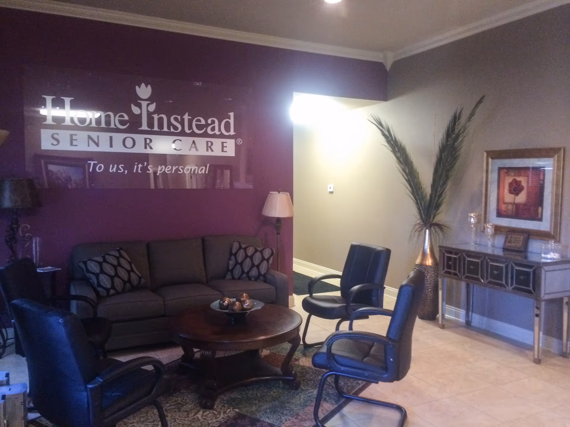 Lobby waiting area with maroon wall logo, couches, chairs, and a coffee table.