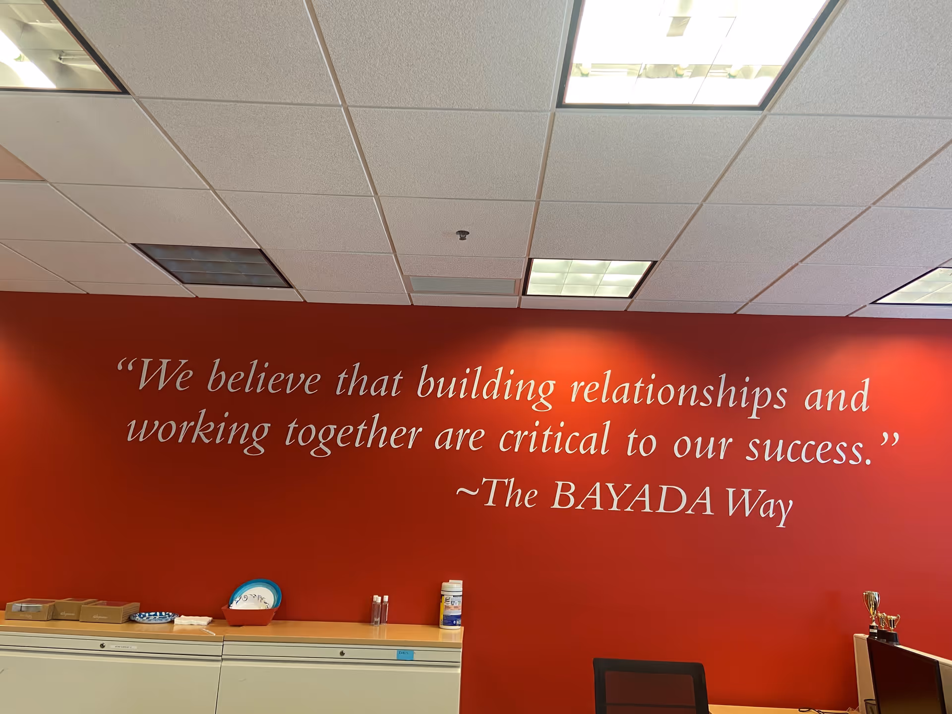 Red wall features a BAYADA quote mural with office furniture.