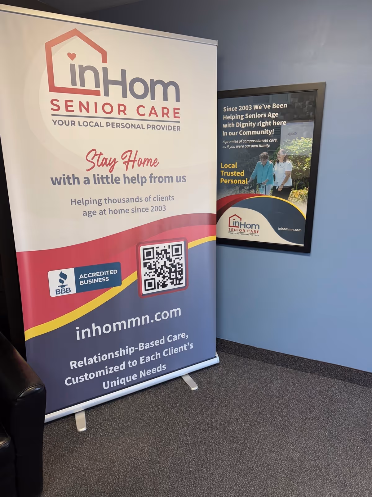 Indoor scene with a large inHom Senior Care banner and framed poster.