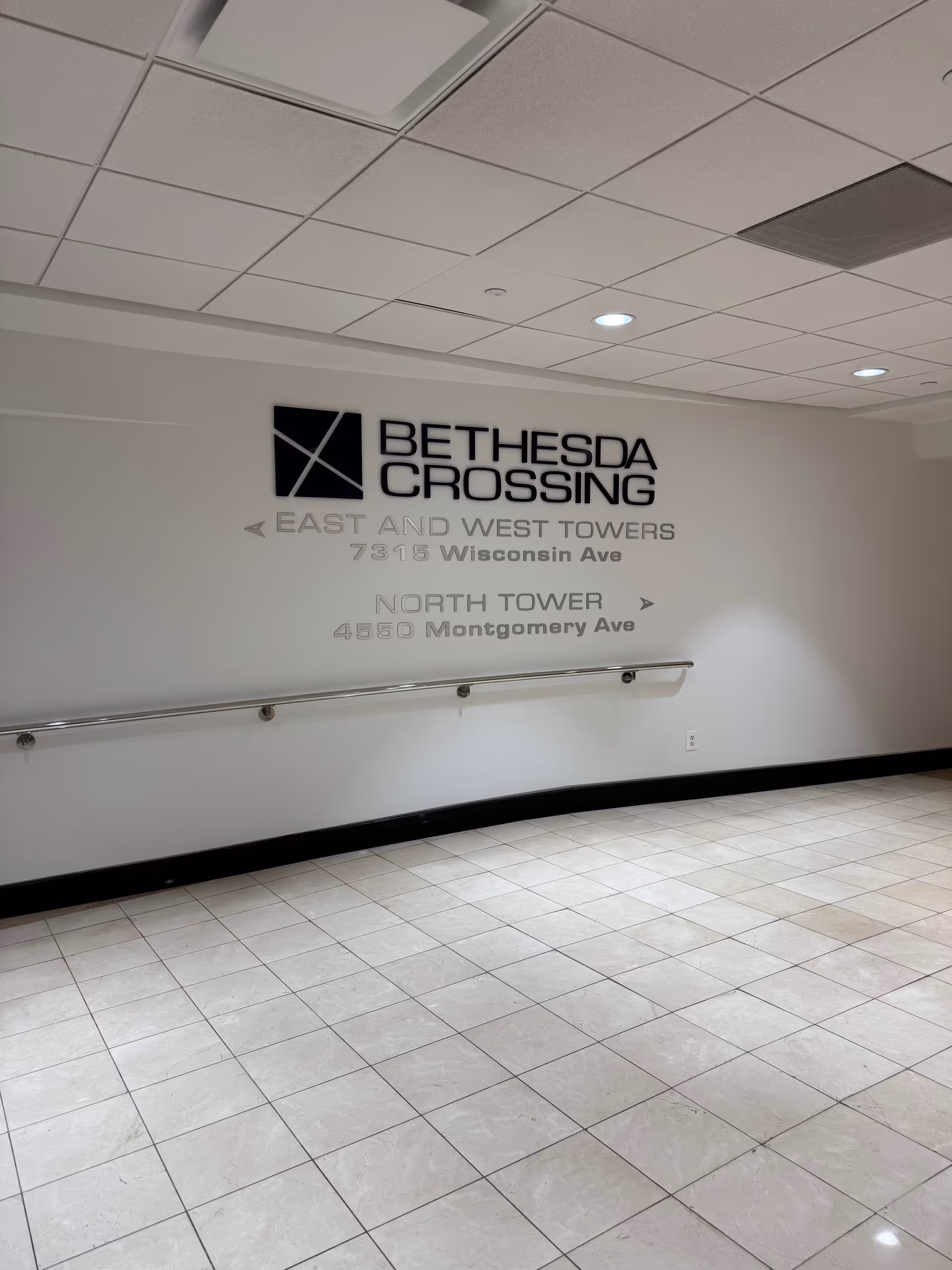 Interior hallway with Bethesda Crossing sign and directional text on a light wall.