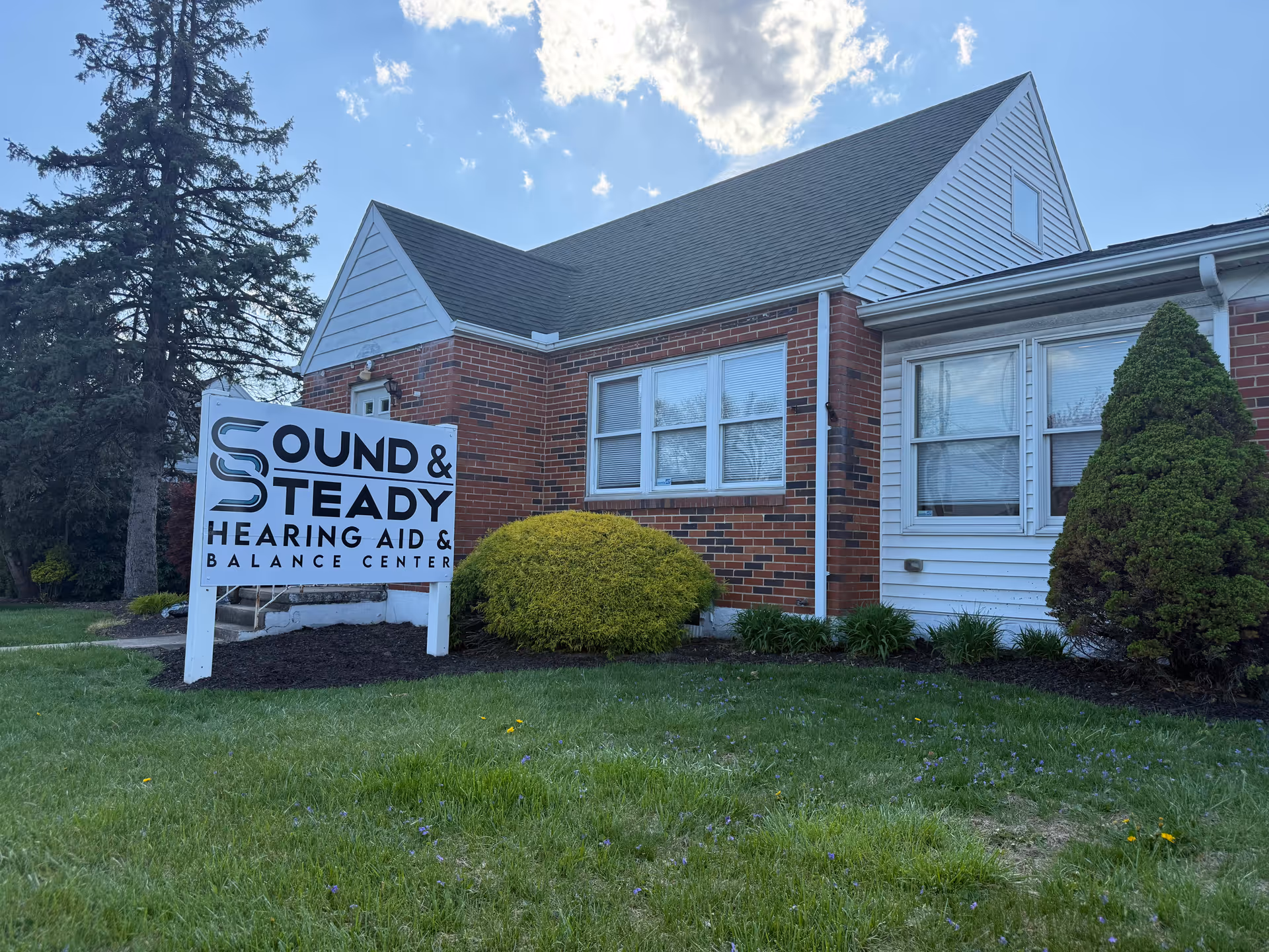 Brick building with a large Sound and Steady Hearing Aid and Balance Center sign on lawn.