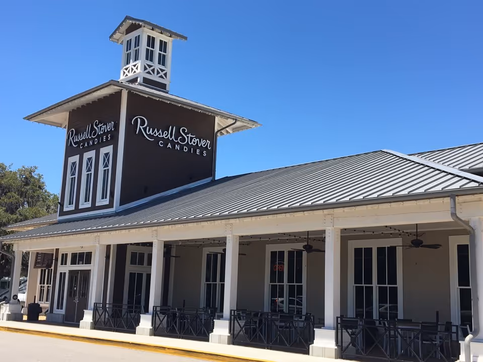 Front view of a Russell Stover Candies storefront with a porch and blue sky.
