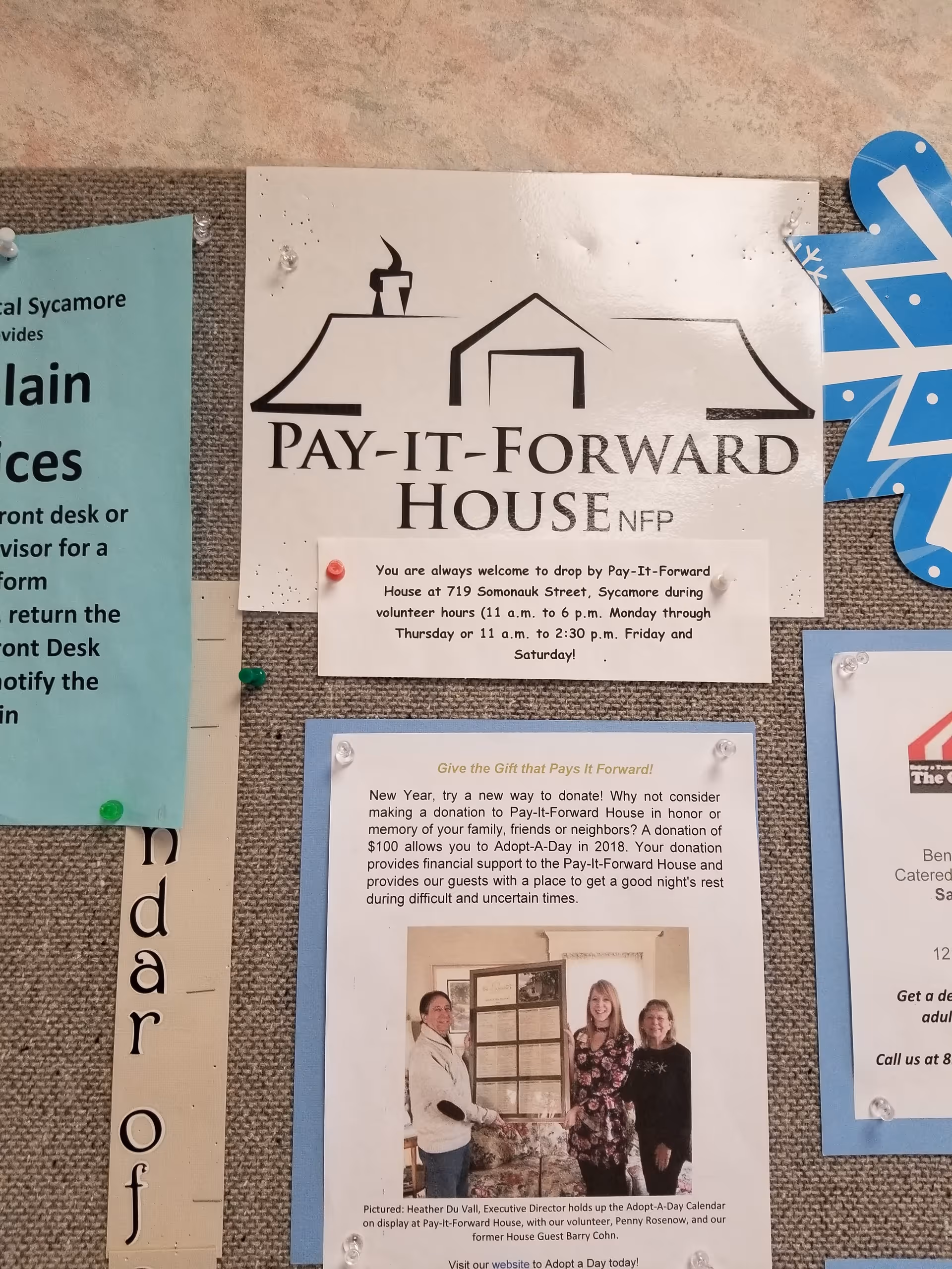 Bulletin board featuring Pay-It-Forward House sign and posted notices.