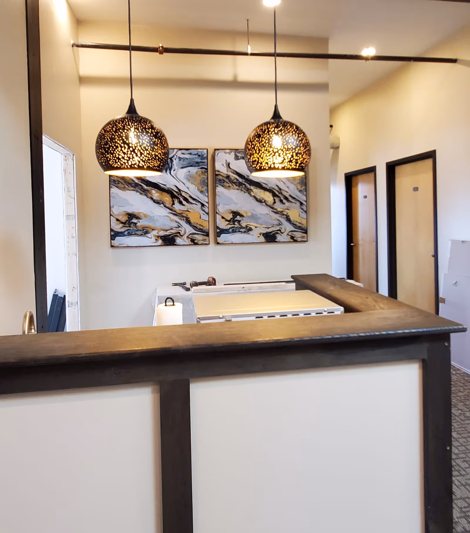 Reception desk with dark wood trim, pendant lights, and abstract wall art inside.