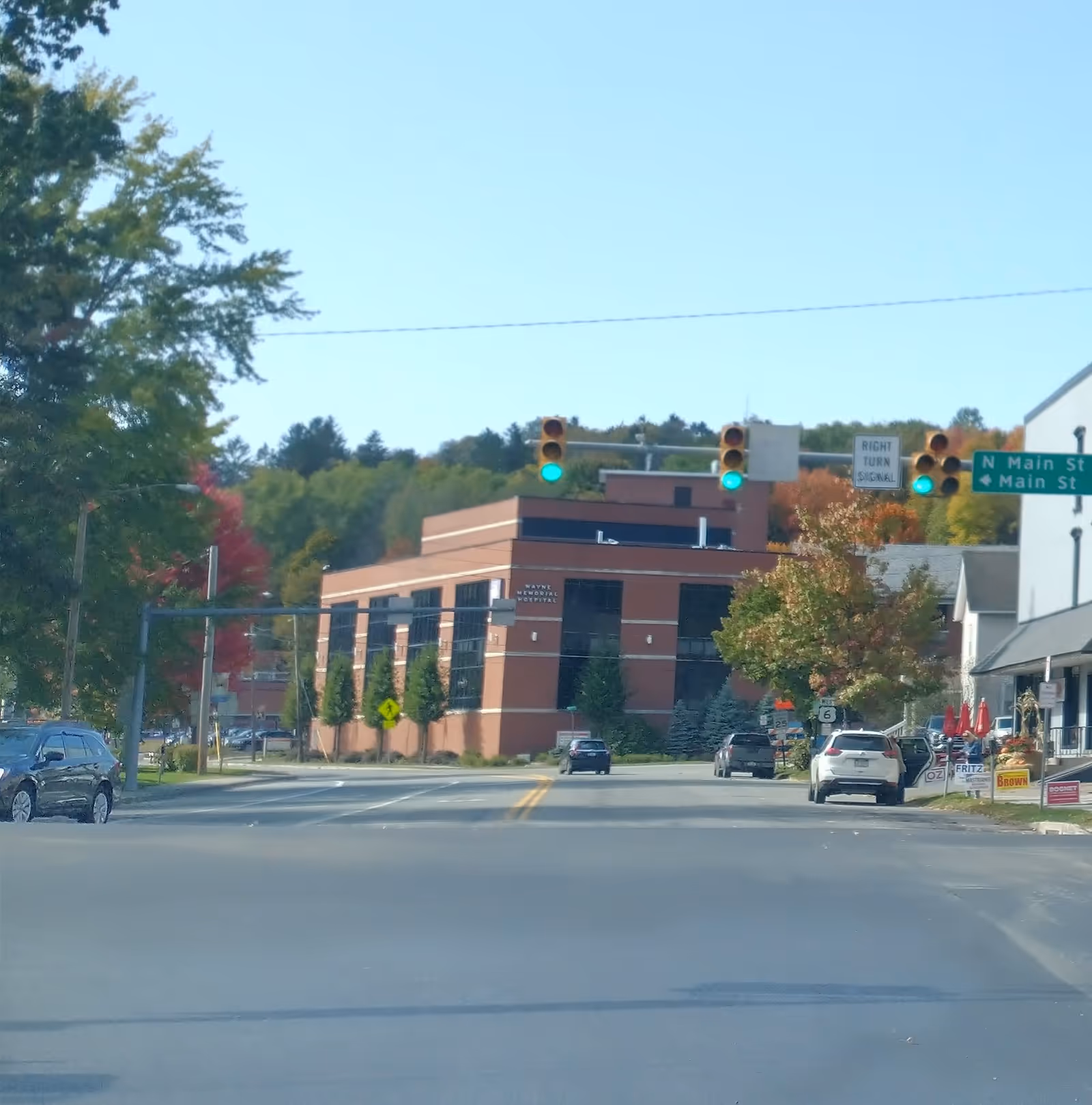Street view with a brick building, traffic lights, and storefronts on a clear day.
