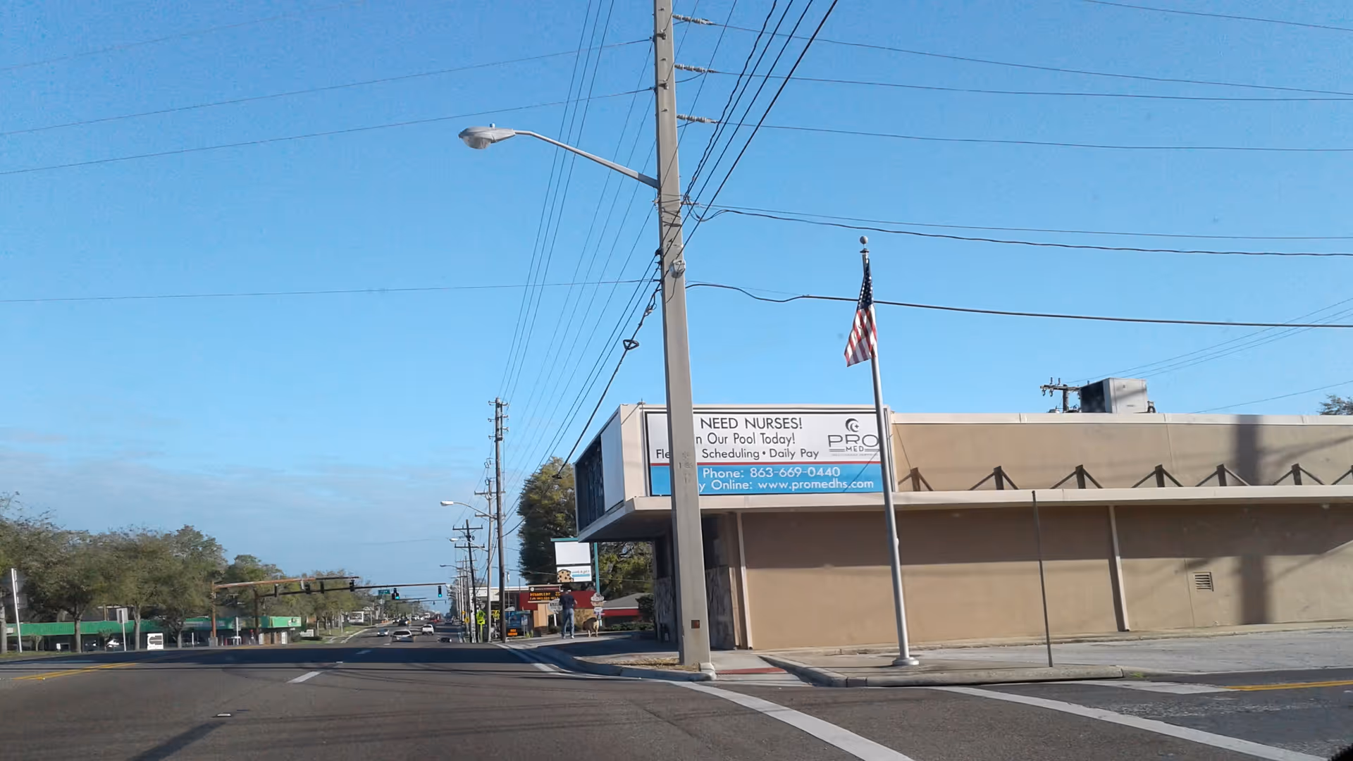 Street view of a beige facility building with a sign and American flag.