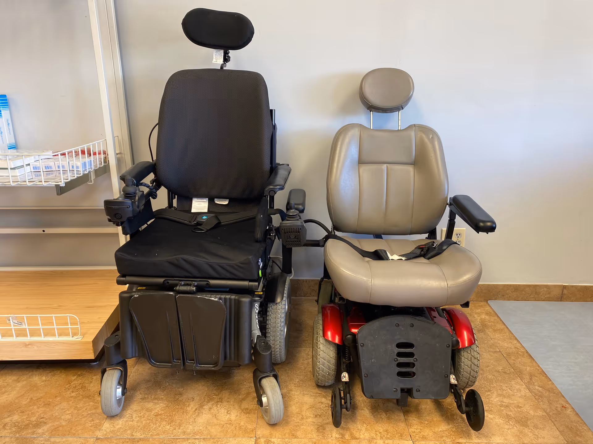 Two motorized wheelchairs parked in a senior living facility hallway.