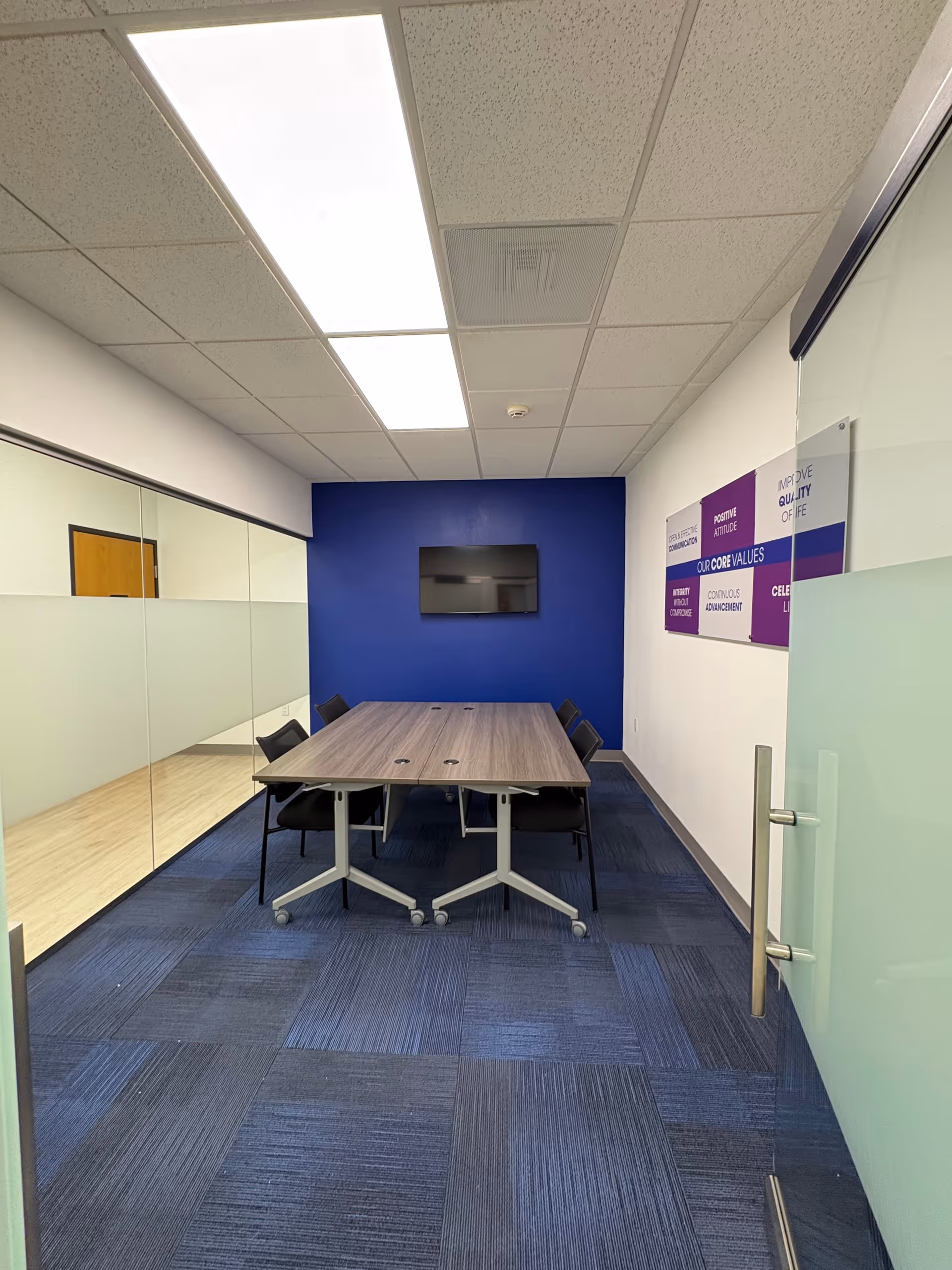 Modern conference room with a long table, chairs, and a blue accent wall.