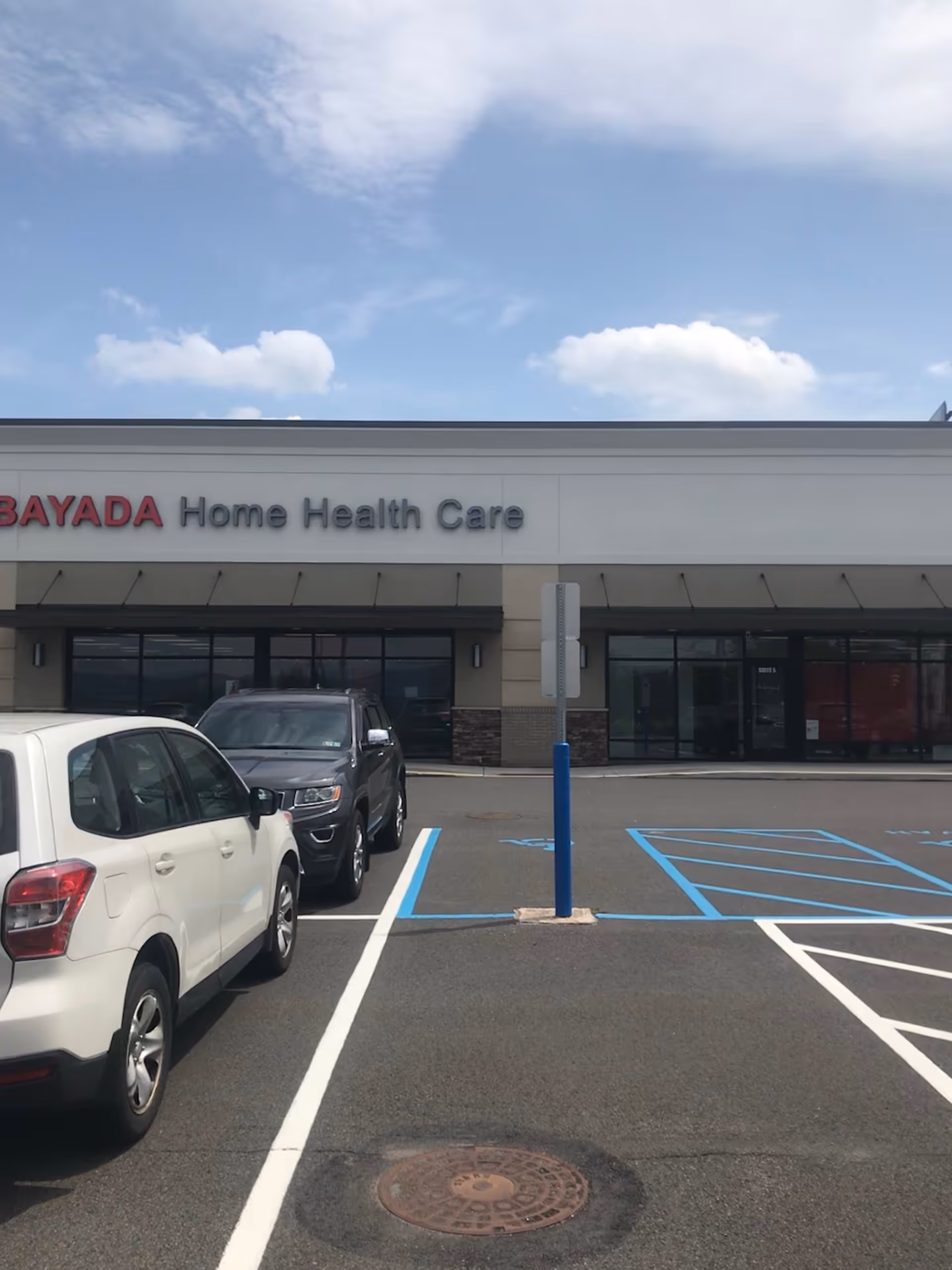 Front exterior of BAYADA Home Health Care with parked cars in a lot.