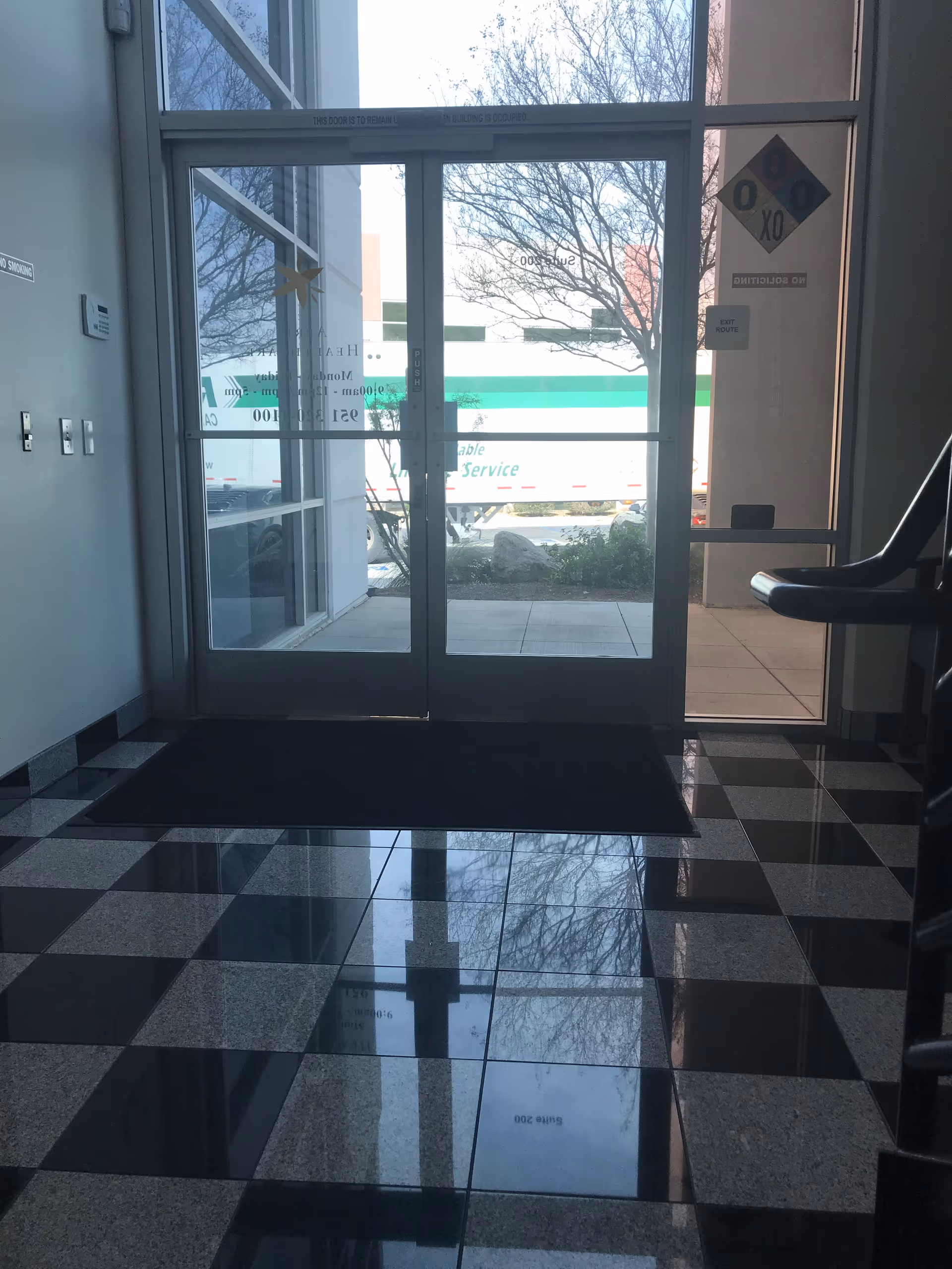 Lobby entry with glass doors, black and white tiled floor, view of outside delivery truck.