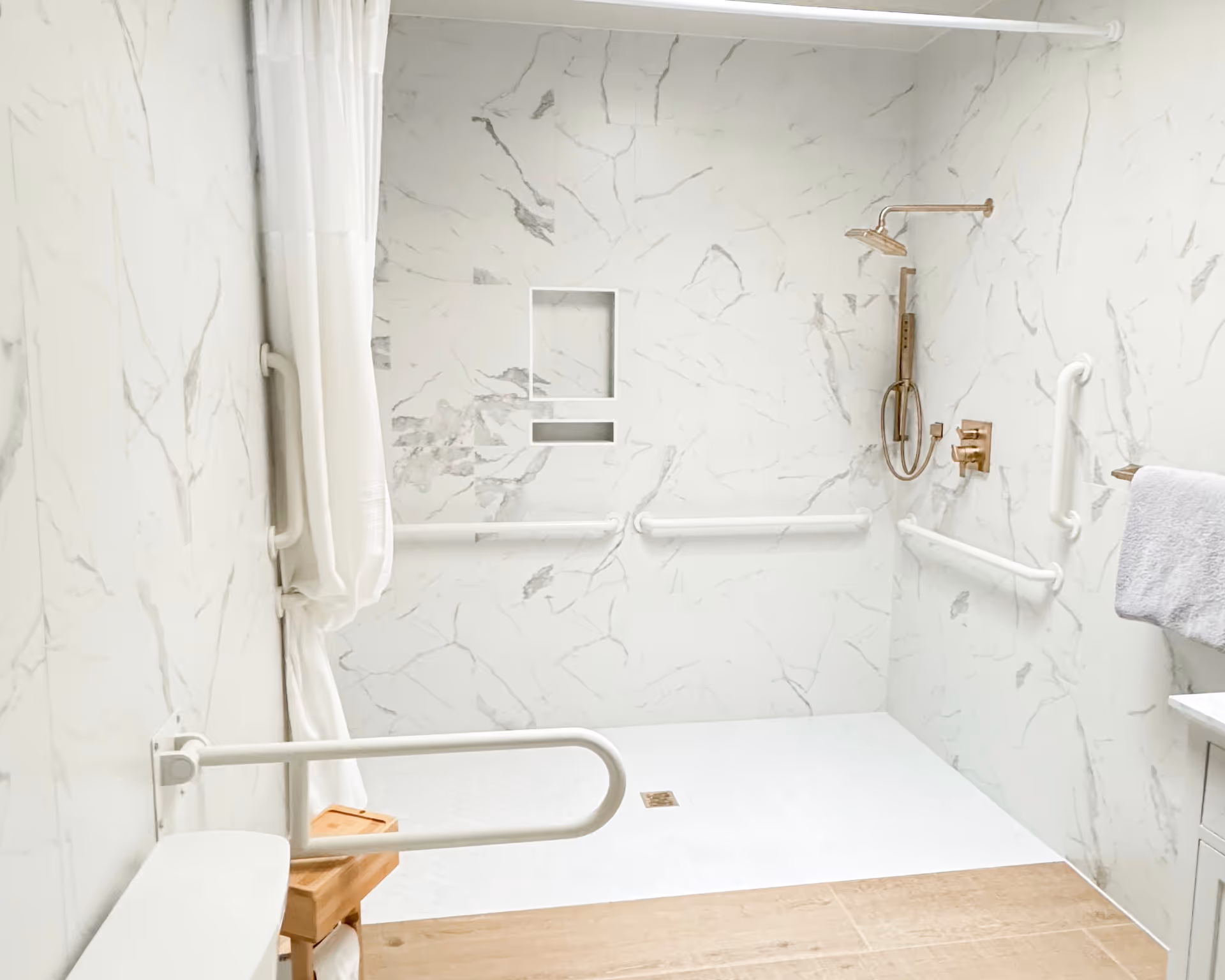 Accessible bathroom with marble pattern walls, a shower, grab bars, and curtain.