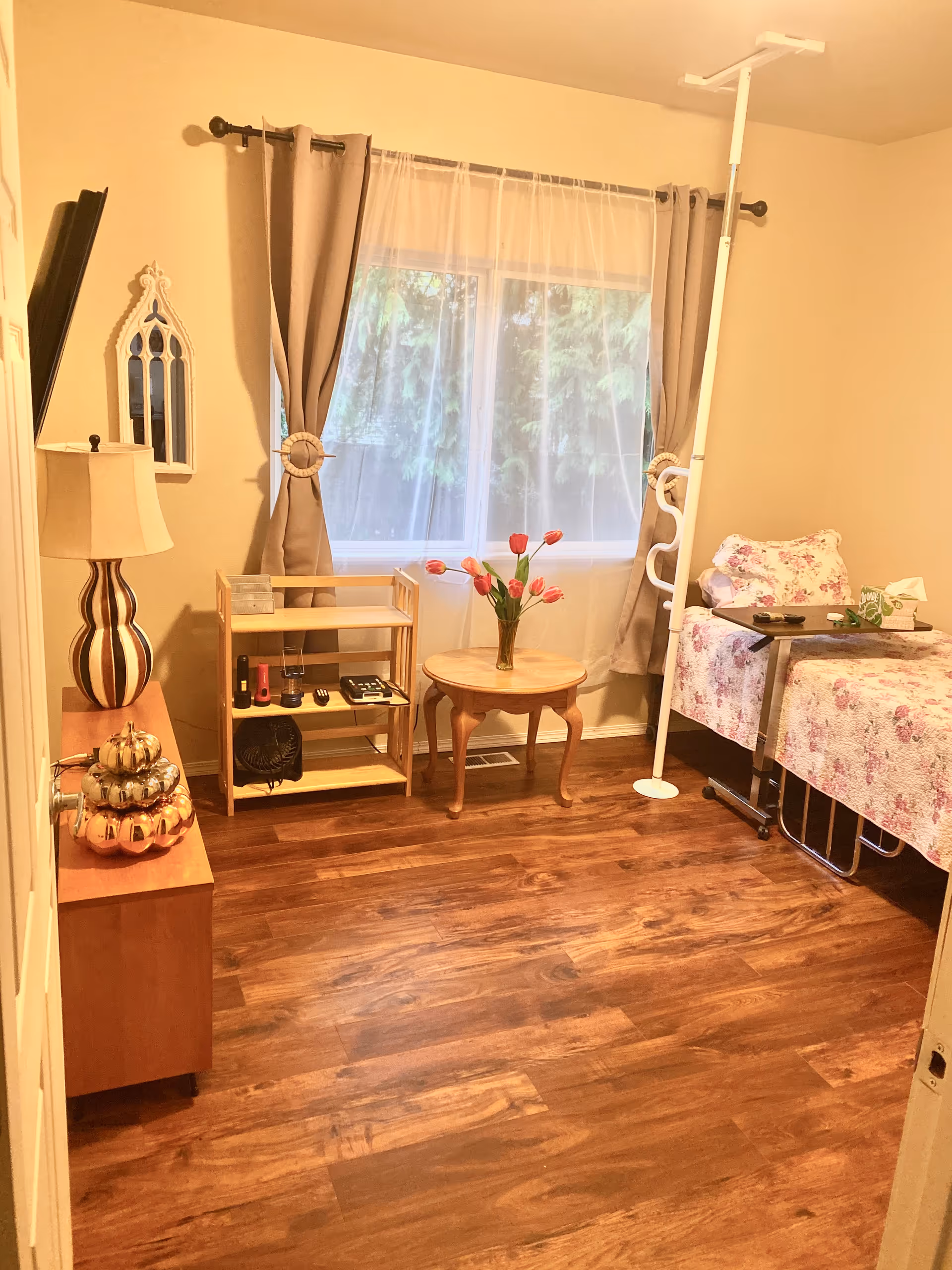 Cozy bedroom in a senior living home with floral bedspread, window, and small table.