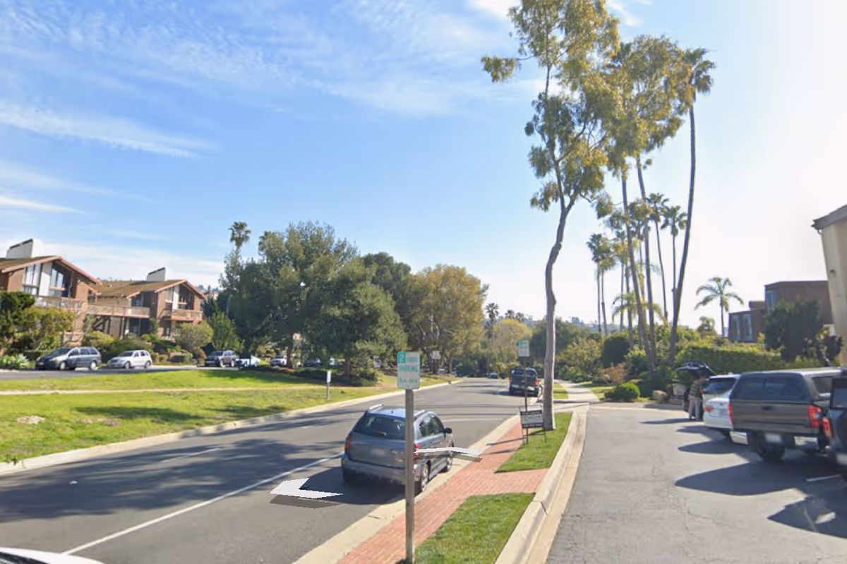 A sunny residential street lined with palm trees, parked cars, and low-rise senior housing buildings.