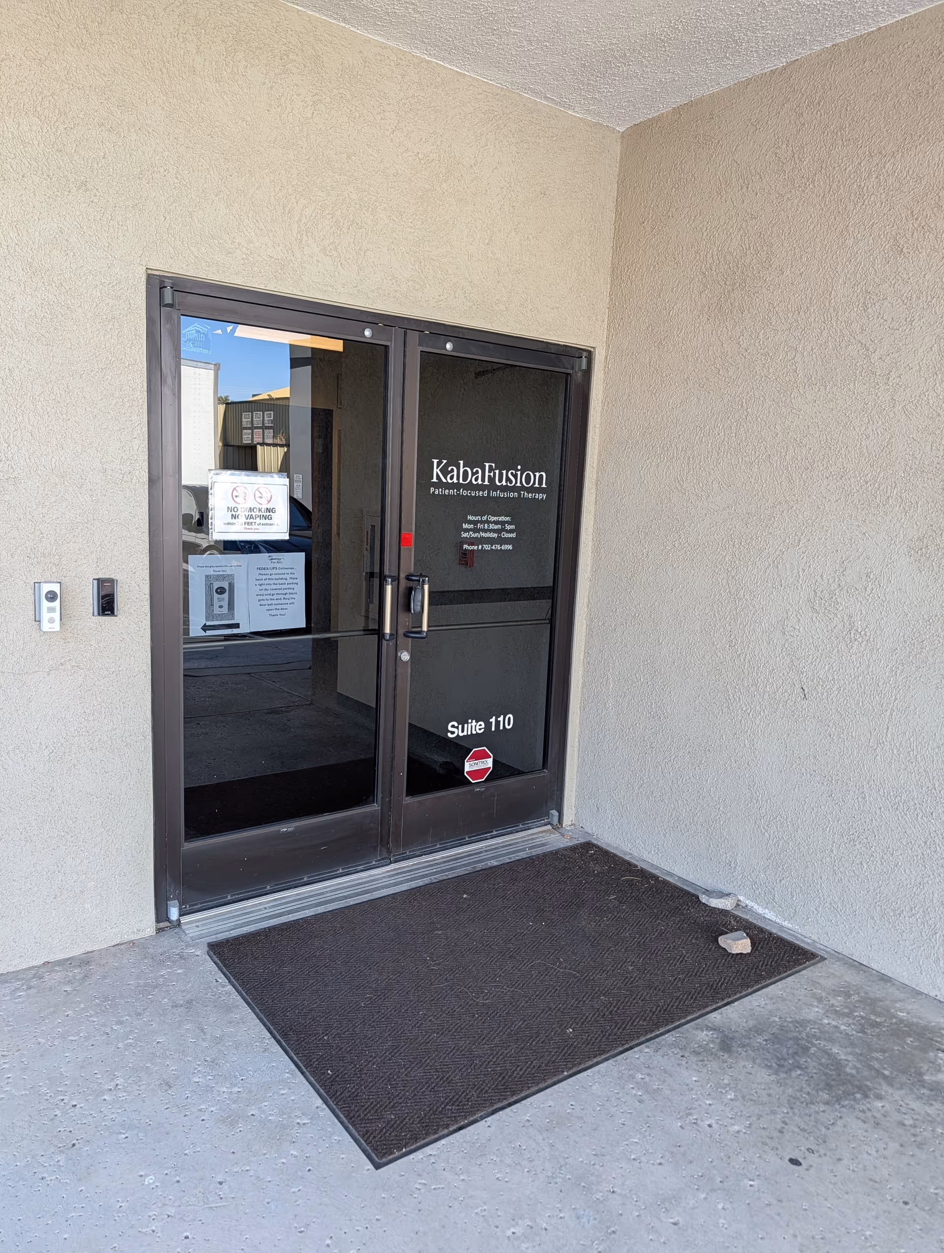 Exterior entrance with glass doors labeled KabaFusion, beige walls, and a black mat.