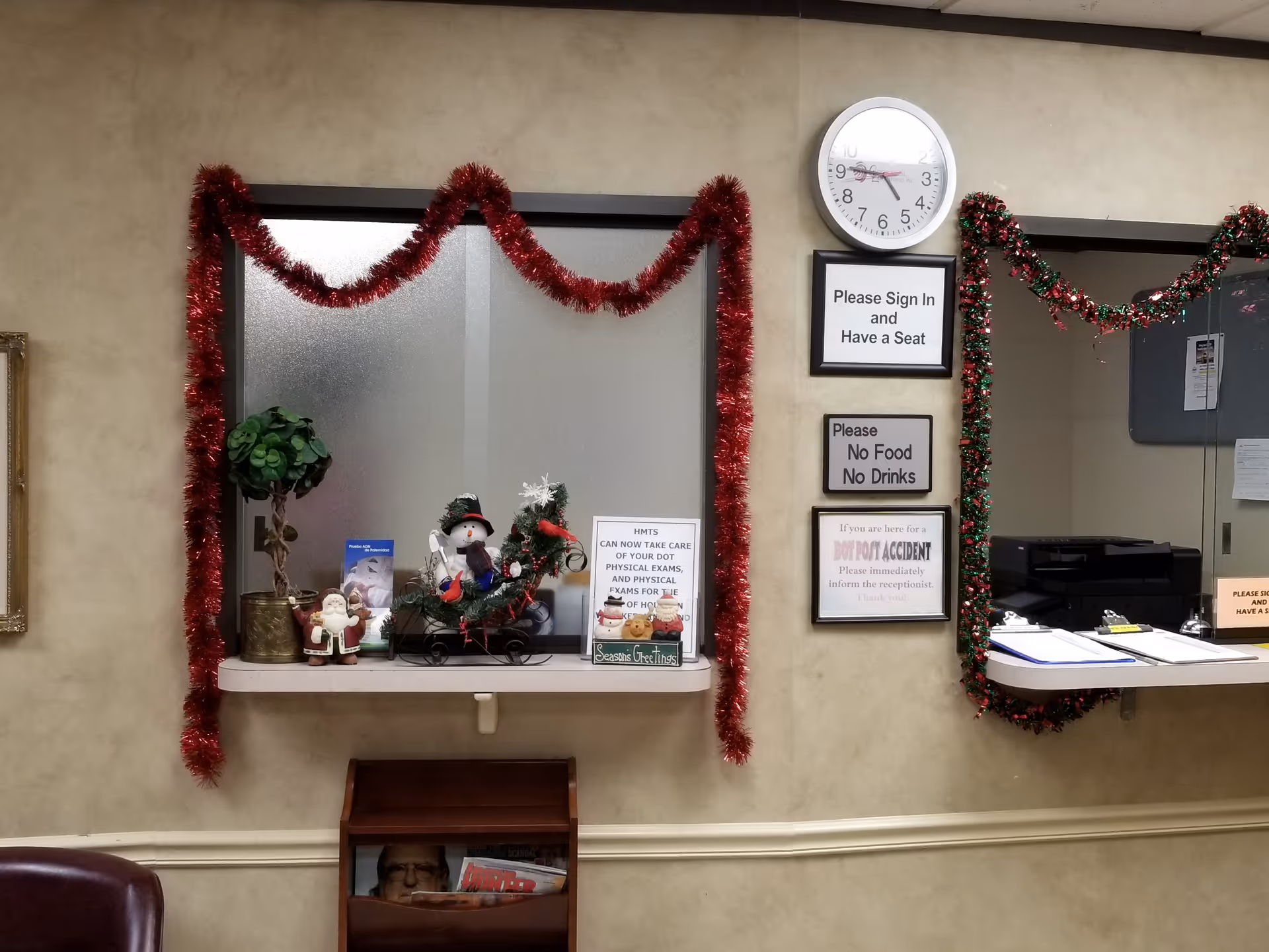 Decorated front desk area with garlands, signs, clock, and holiday arrangements inside a facility