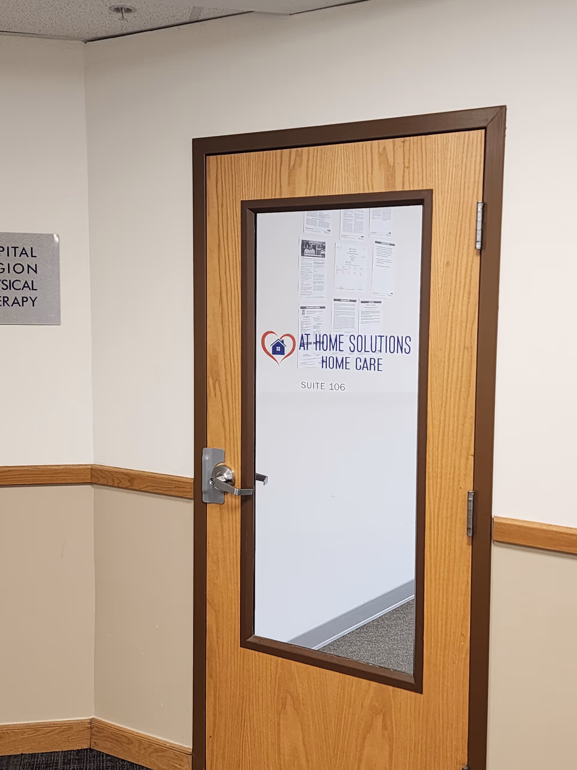 Wooden door with frosted glass shows At Home Solutions Home Care and Suite 106.