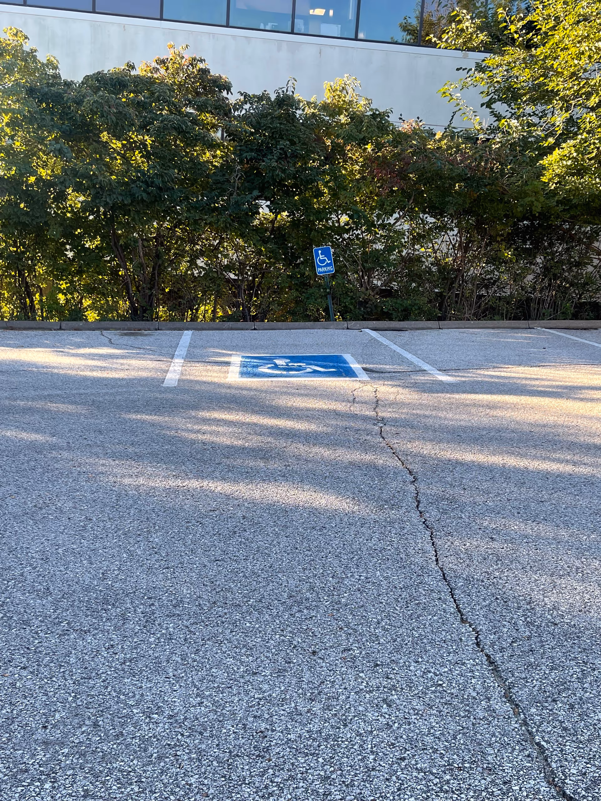 Parking lot outside St. Croix Hospice with a wheelchair-accessible space and surrounding greenery.