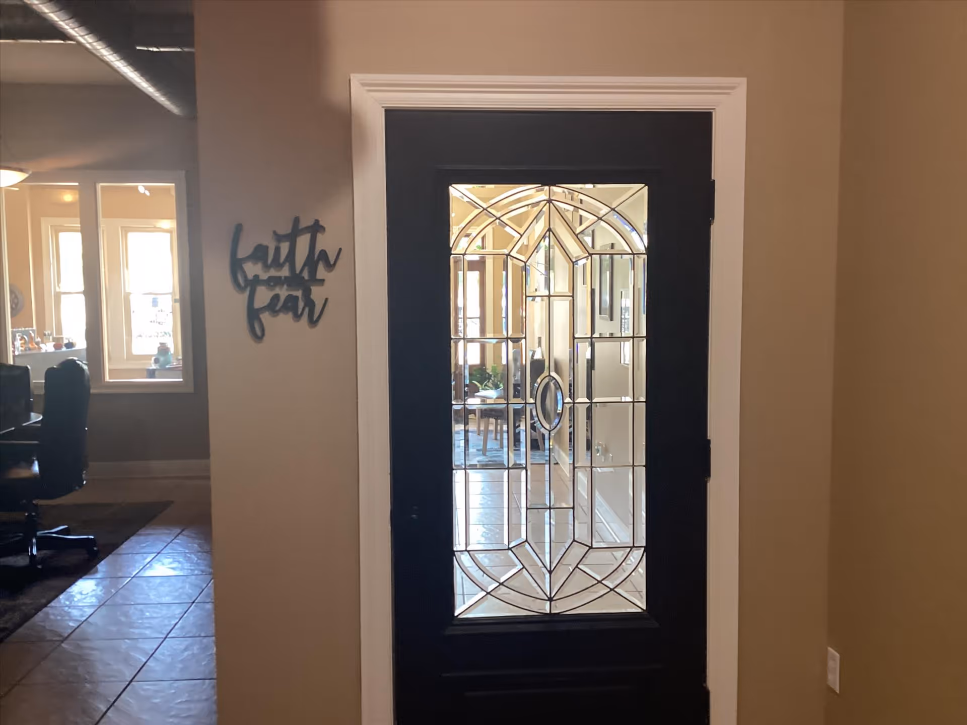 Interior hallway with a decorative glass door and a 'Faith Fear' sign on the wall.