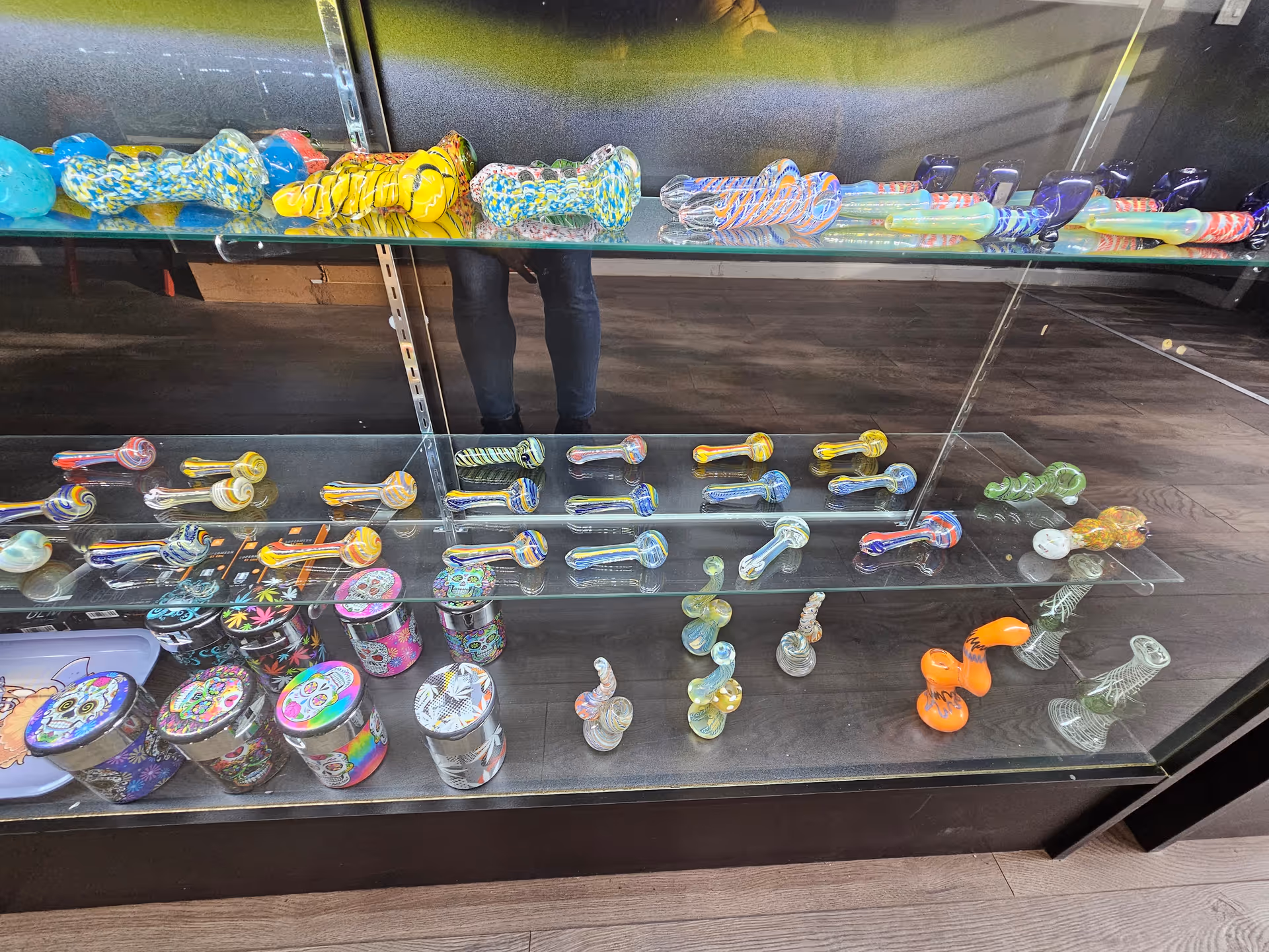 Colorful glass smoking pipes displayed on glass shelves in a shop