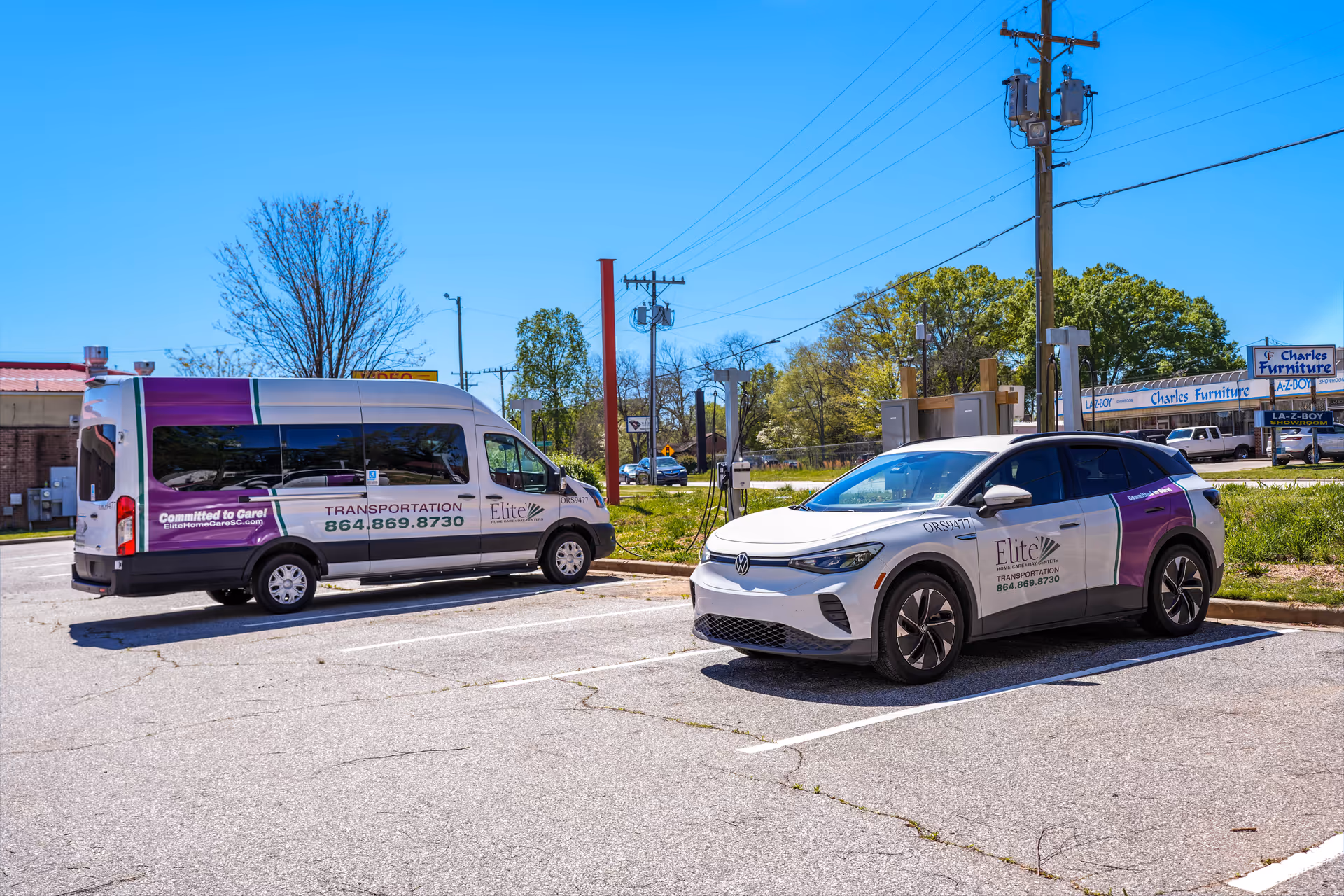 Two Elite Transportation vehicles parked in a lot beside a building on a sunny day.