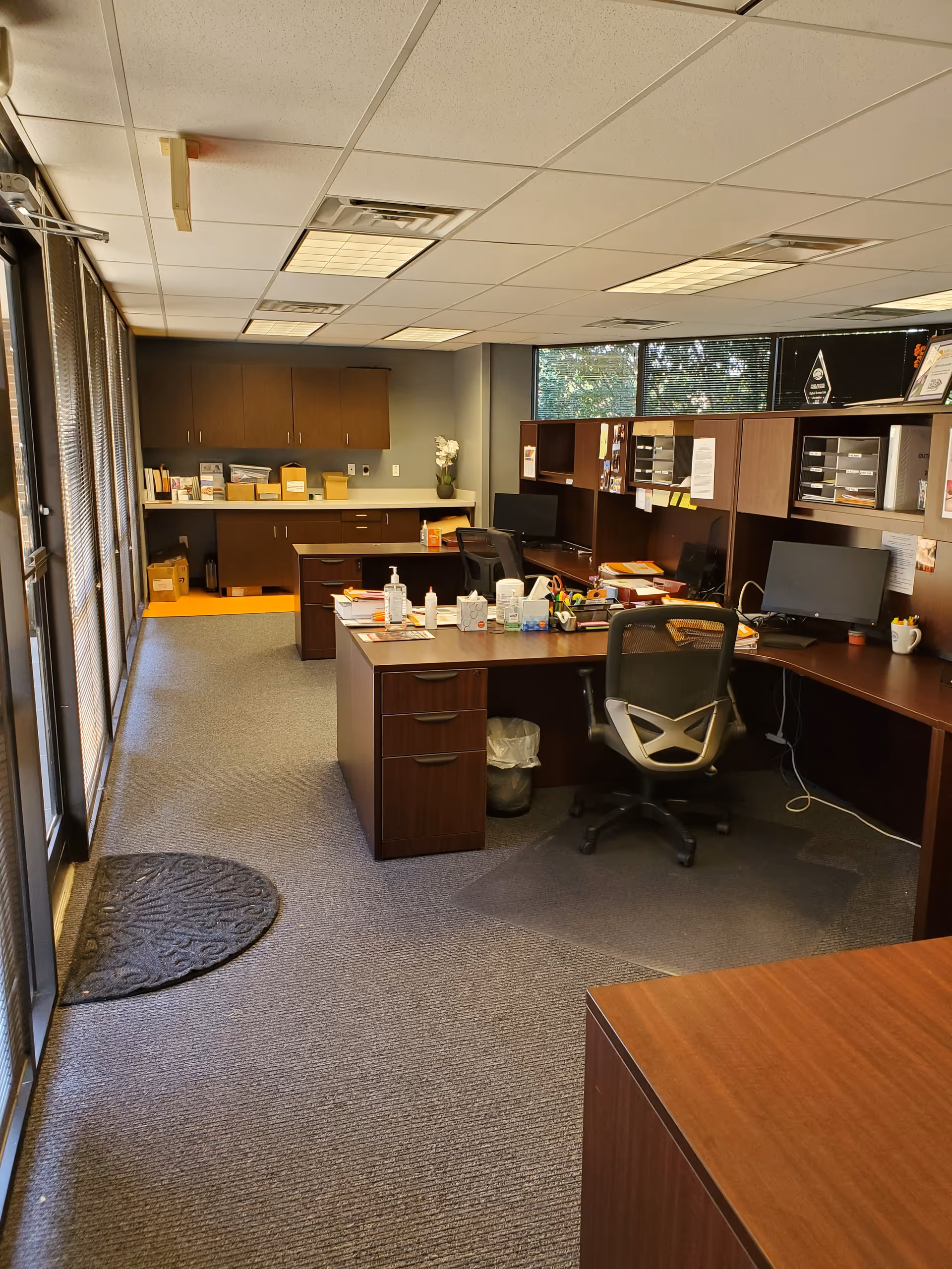 Office workspace with desks, computers, and filing cabinets in an open area.