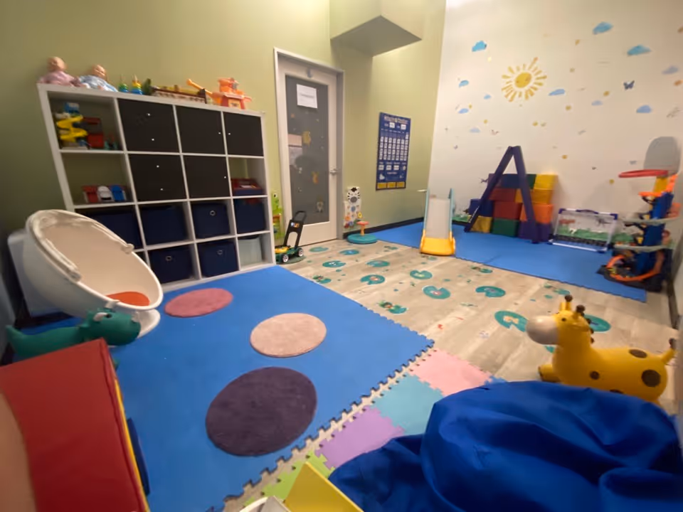 Colorful Kadiant senior living activity room with mats, shelves, and toy giraffe.