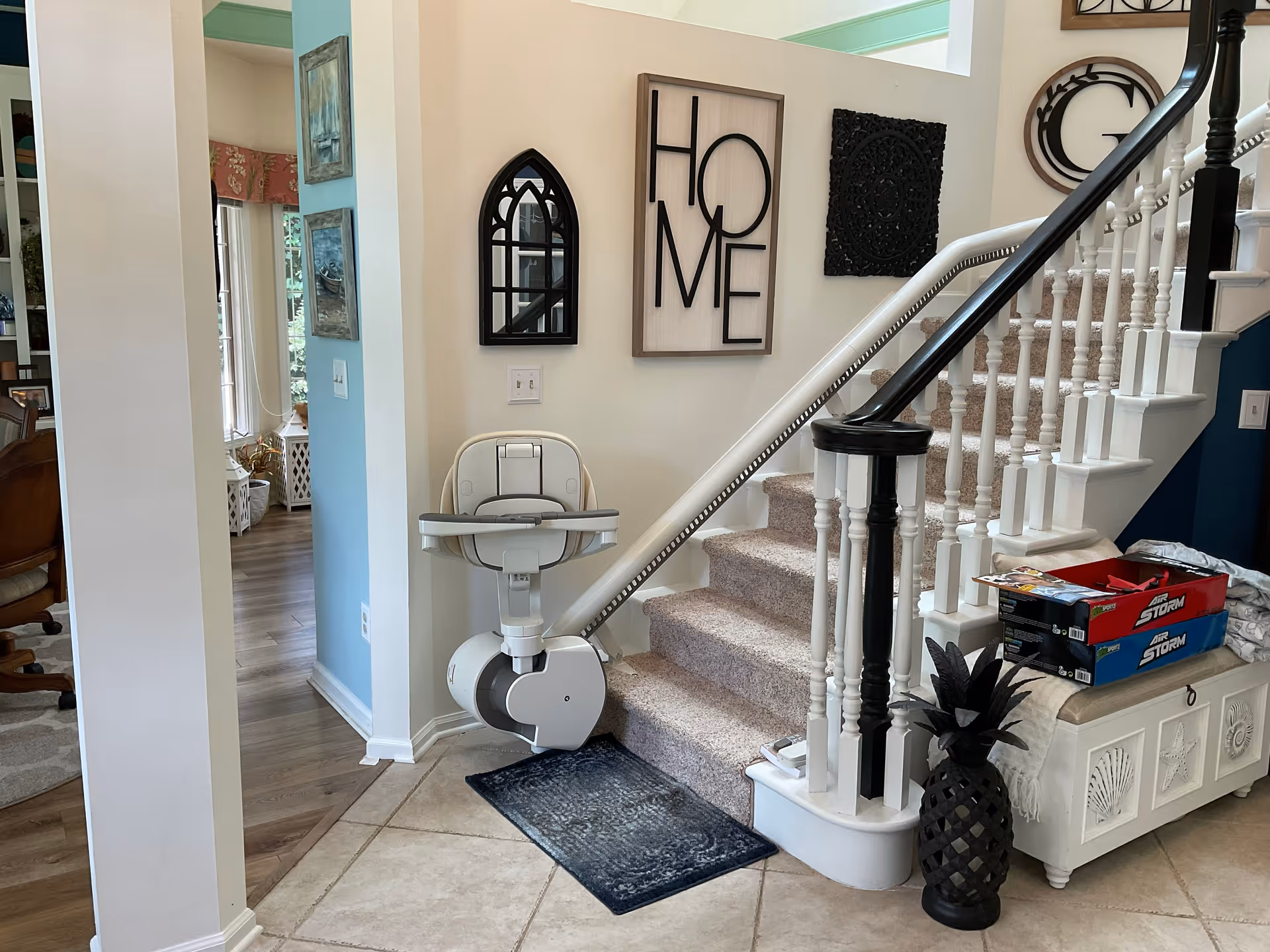 Indoor home foyer featuring a stairlift beside a staircase and decorative wall art.