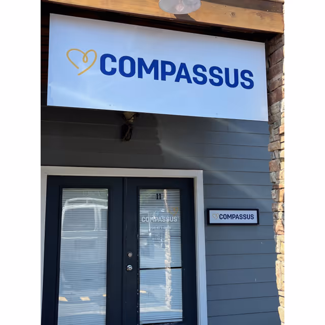 Front entrance of a Compassus senior living facility with a large sign above the door.