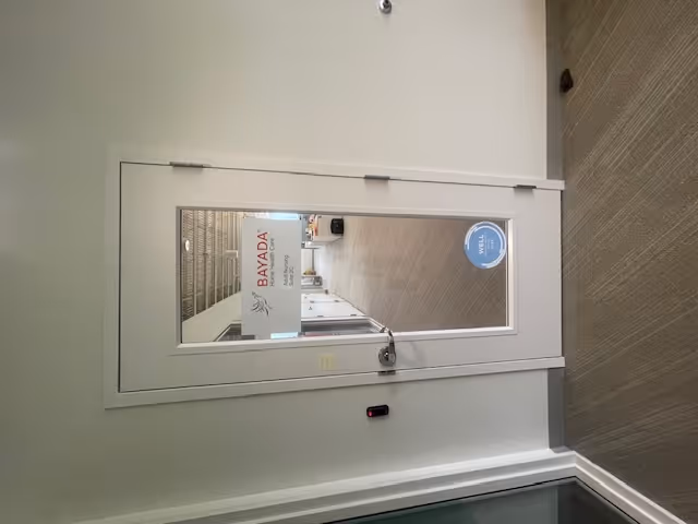 Interior door with BAYADA sign opening to a hallway inside a nursing facility.