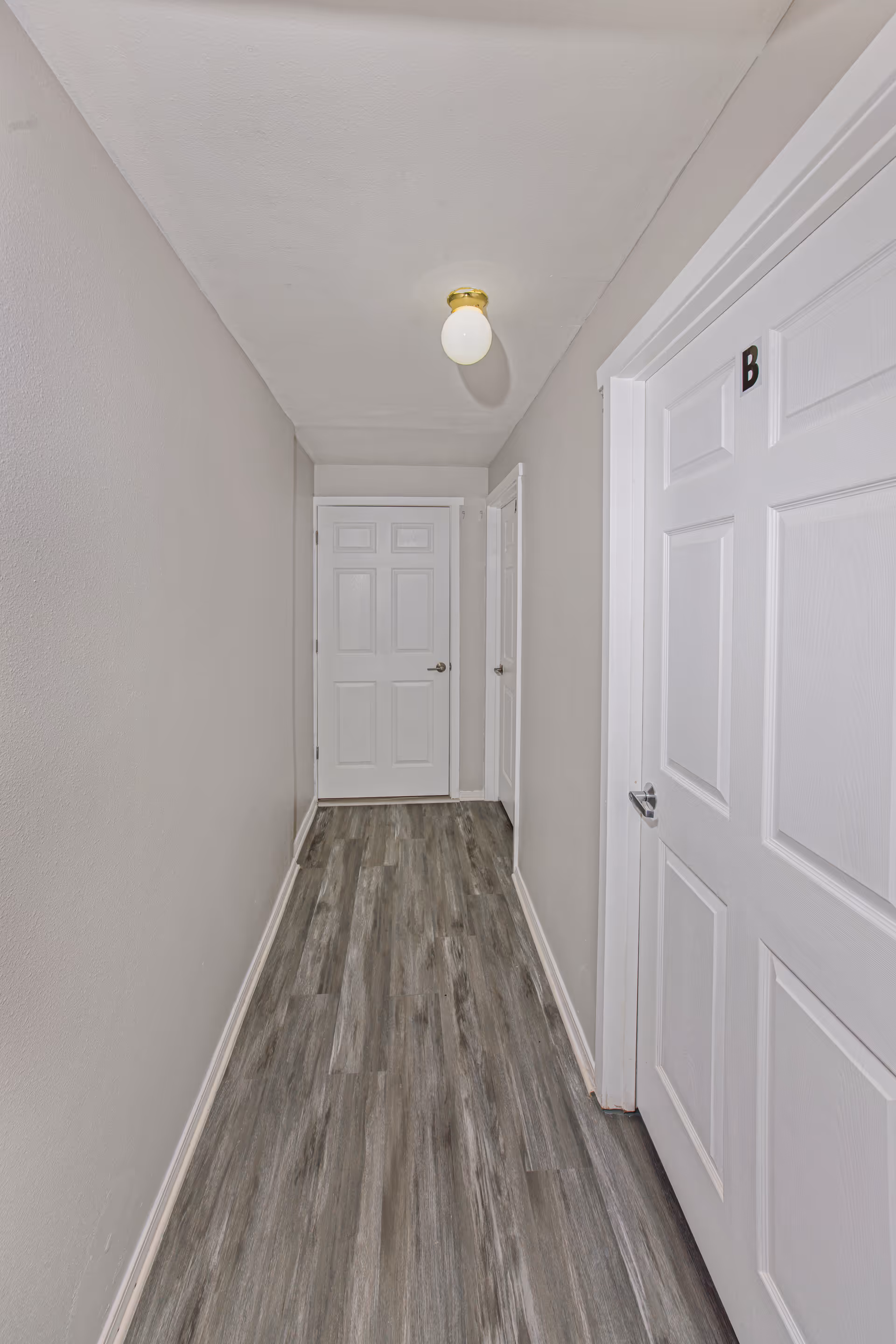 Narrow hallway in Clover Care Adult Family Home with white doors and gray flooring.