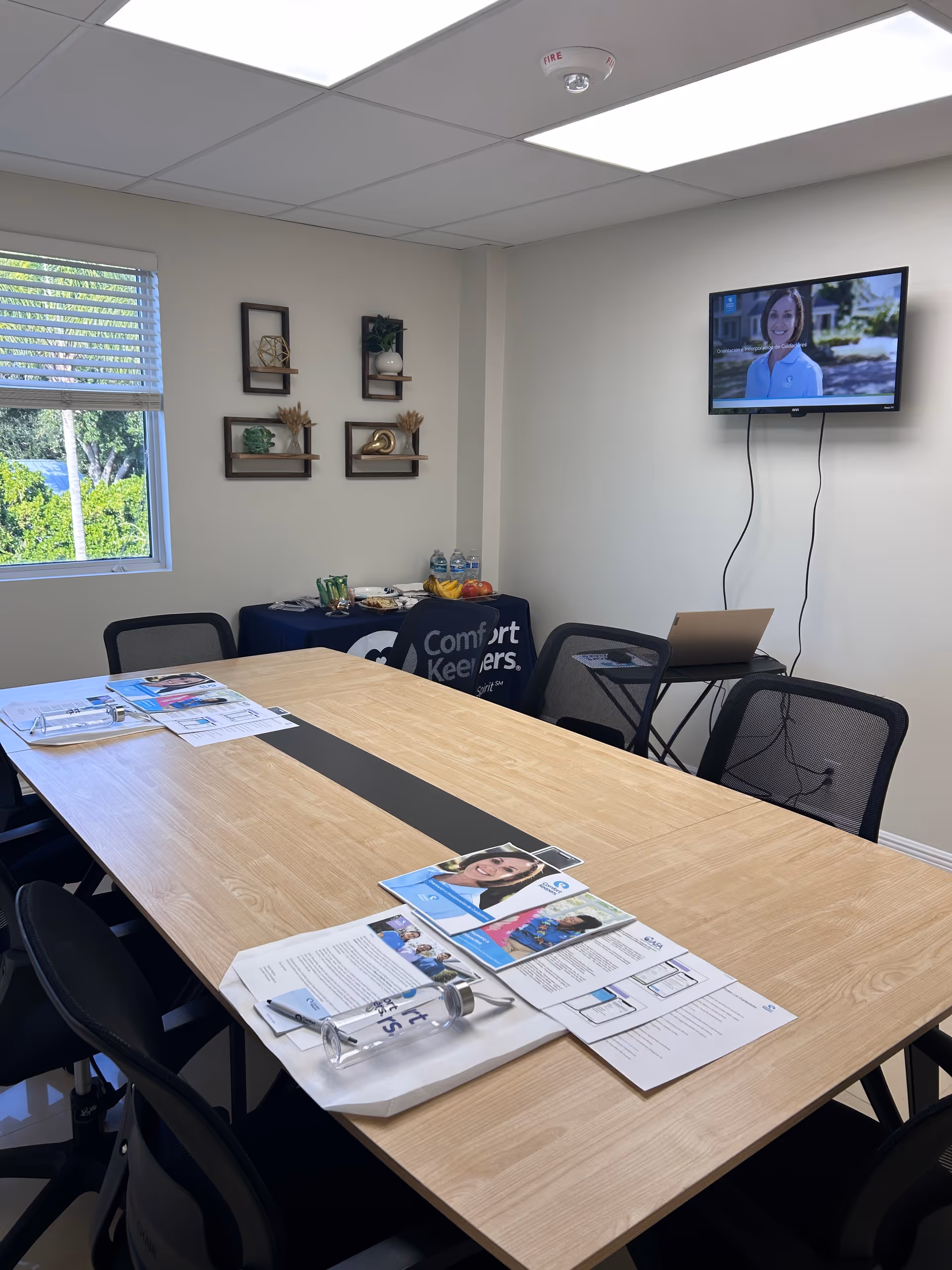 A conference room in a Comfort Keepers facility with a long table, chairs, and TV.