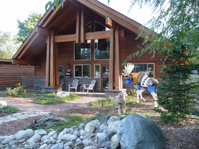 Wooden lodge-style facility exterior with front entrance and outdoor seating.
